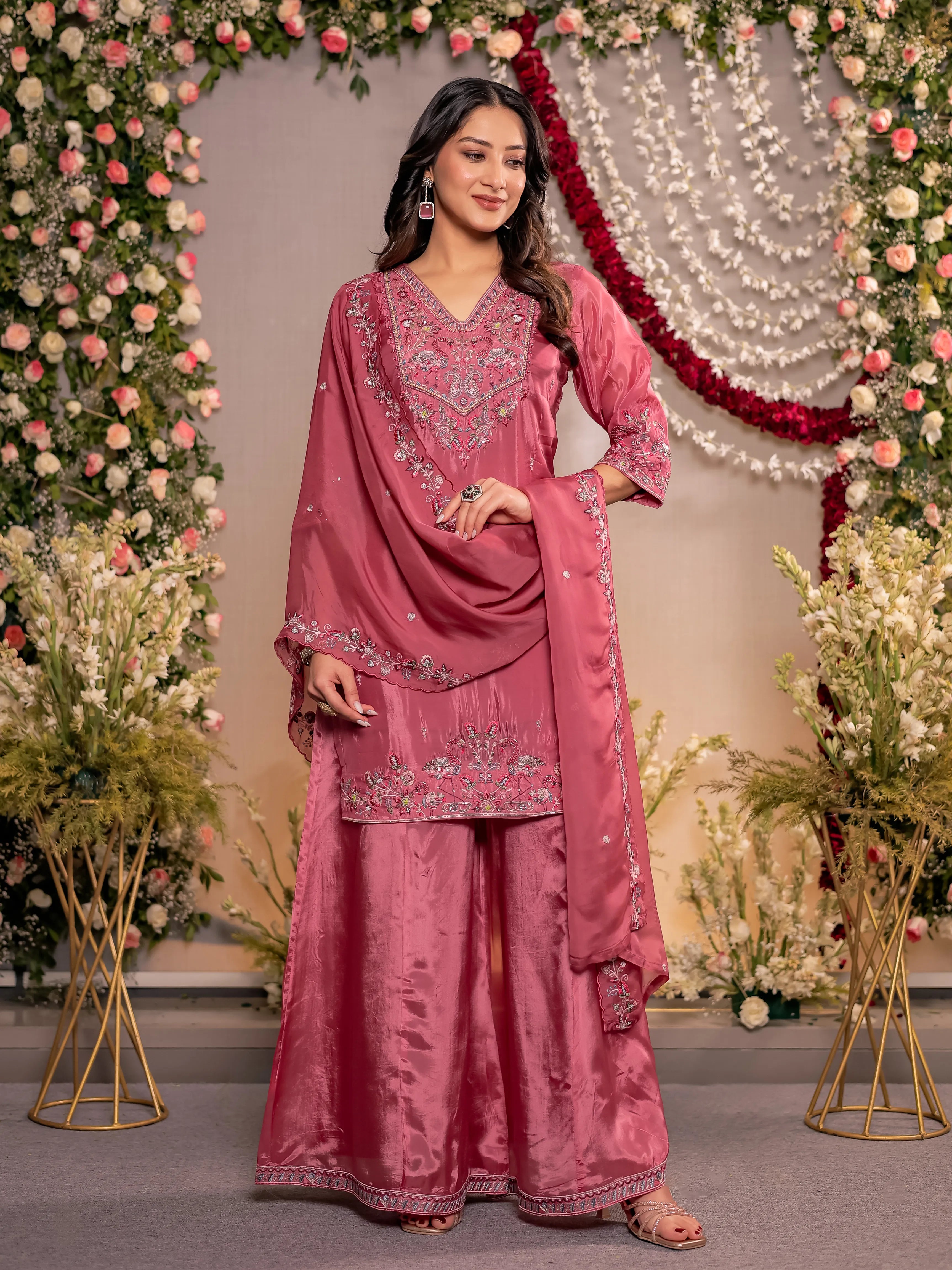 Woman in a pink traditional outfit with floral decorations in the background