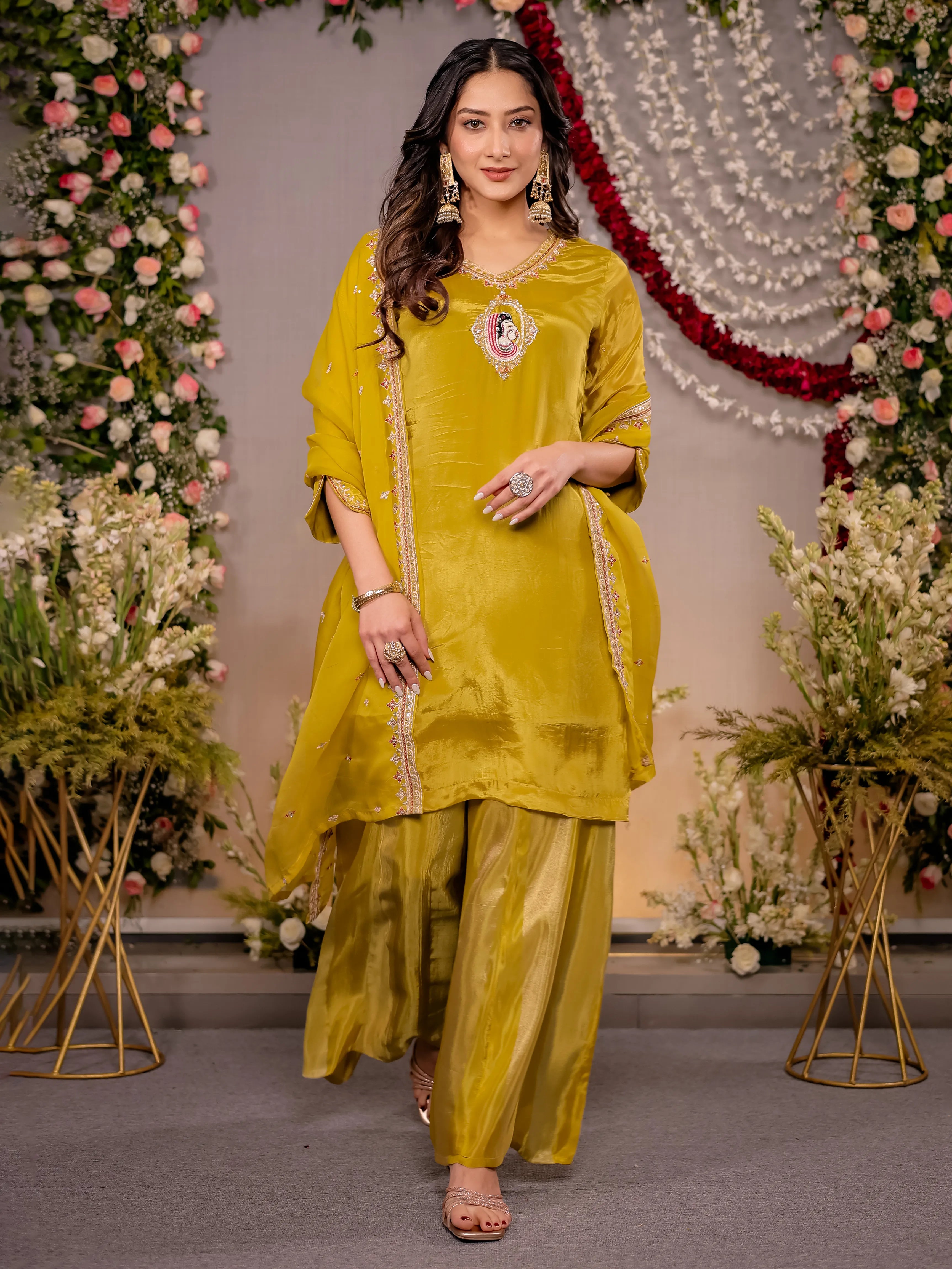 Woman in a yellow traditional outfit standing in front of floral decorations