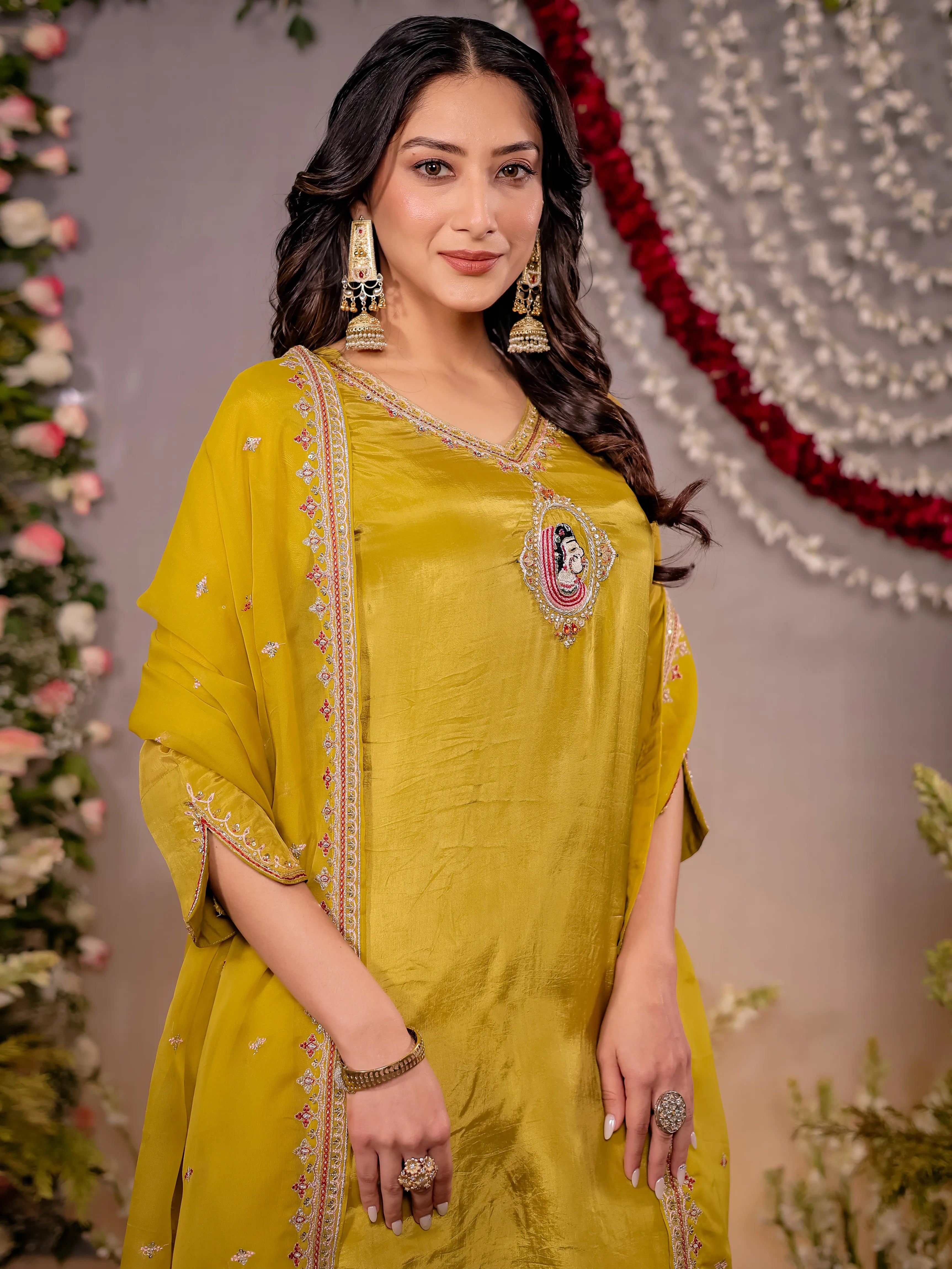 Woman in a yellow traditional outfit with floral decorations in the background
