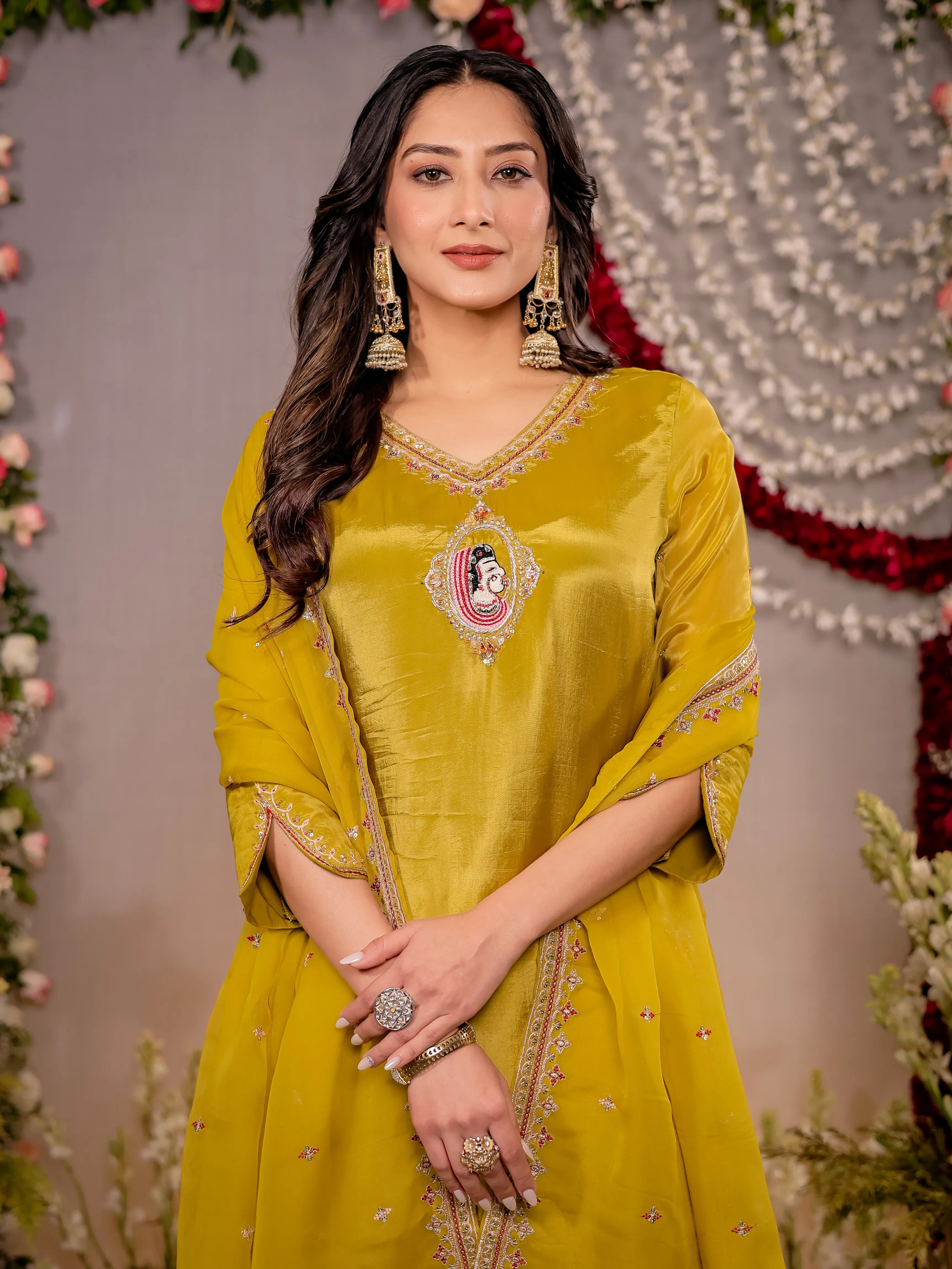 Woman in a yellow traditional outfit with floral decorations in the background