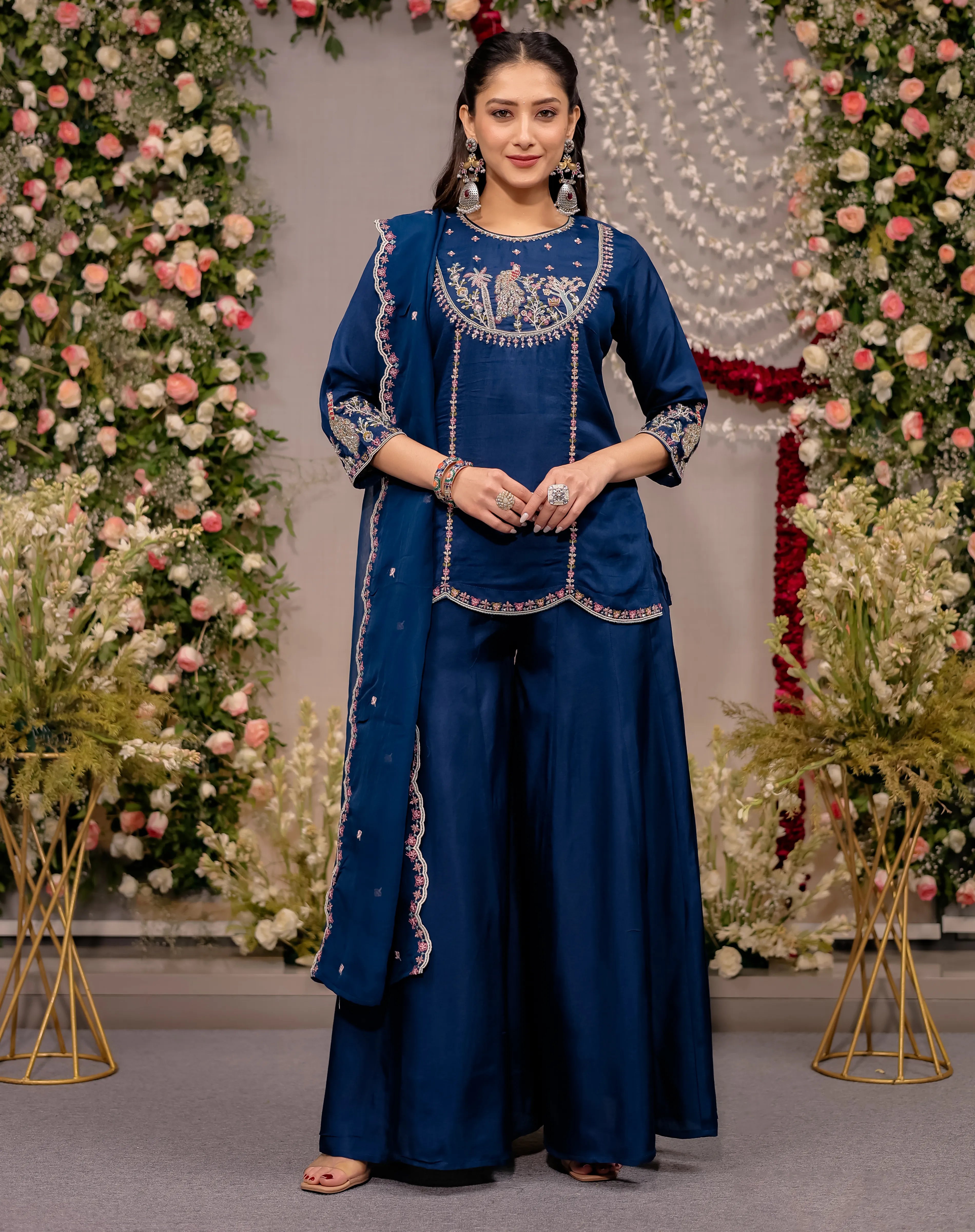 Woman in a blue traditional outfit with floral decorations in the background
