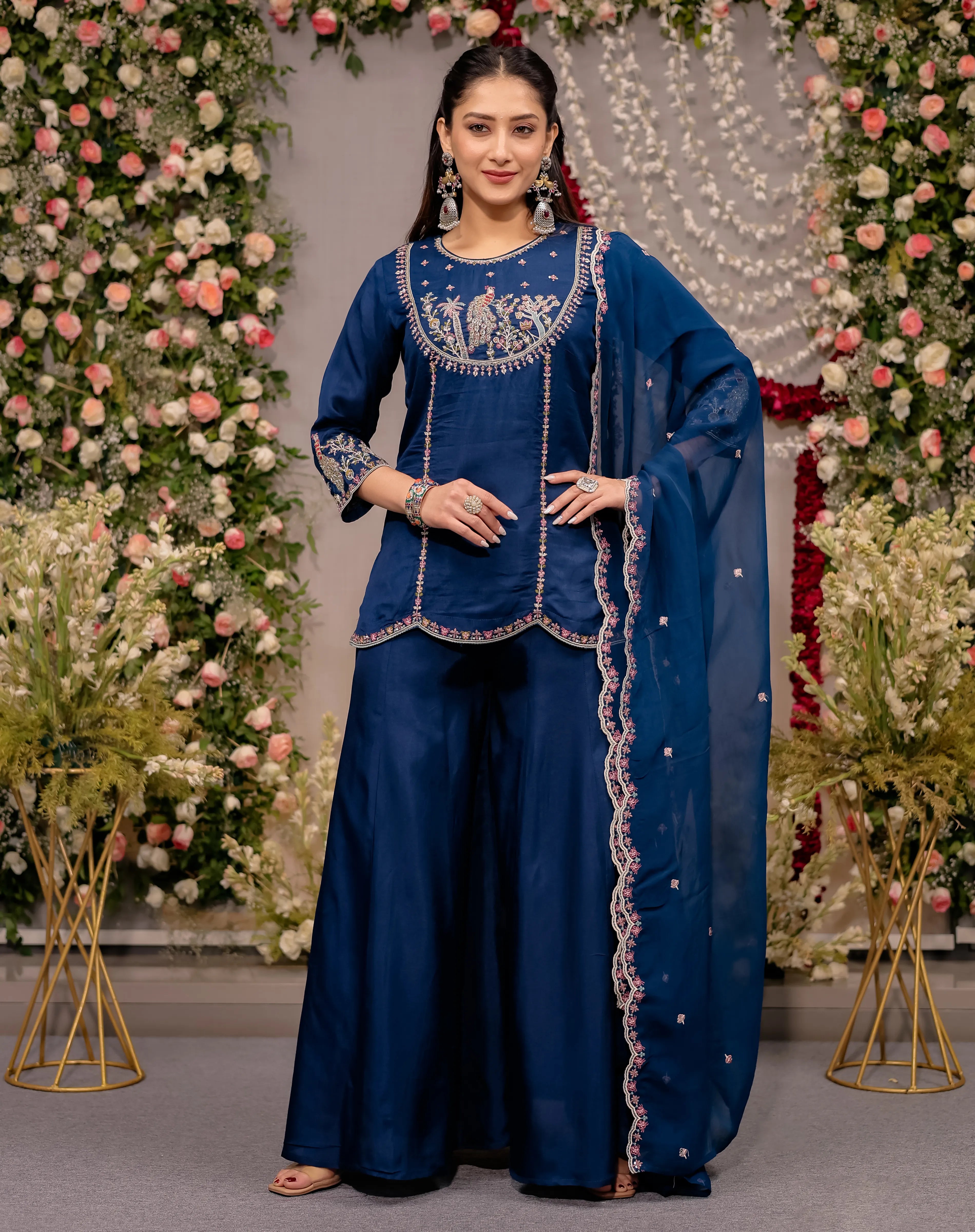 Woman in a blue traditional outfit with floral decorations in the background