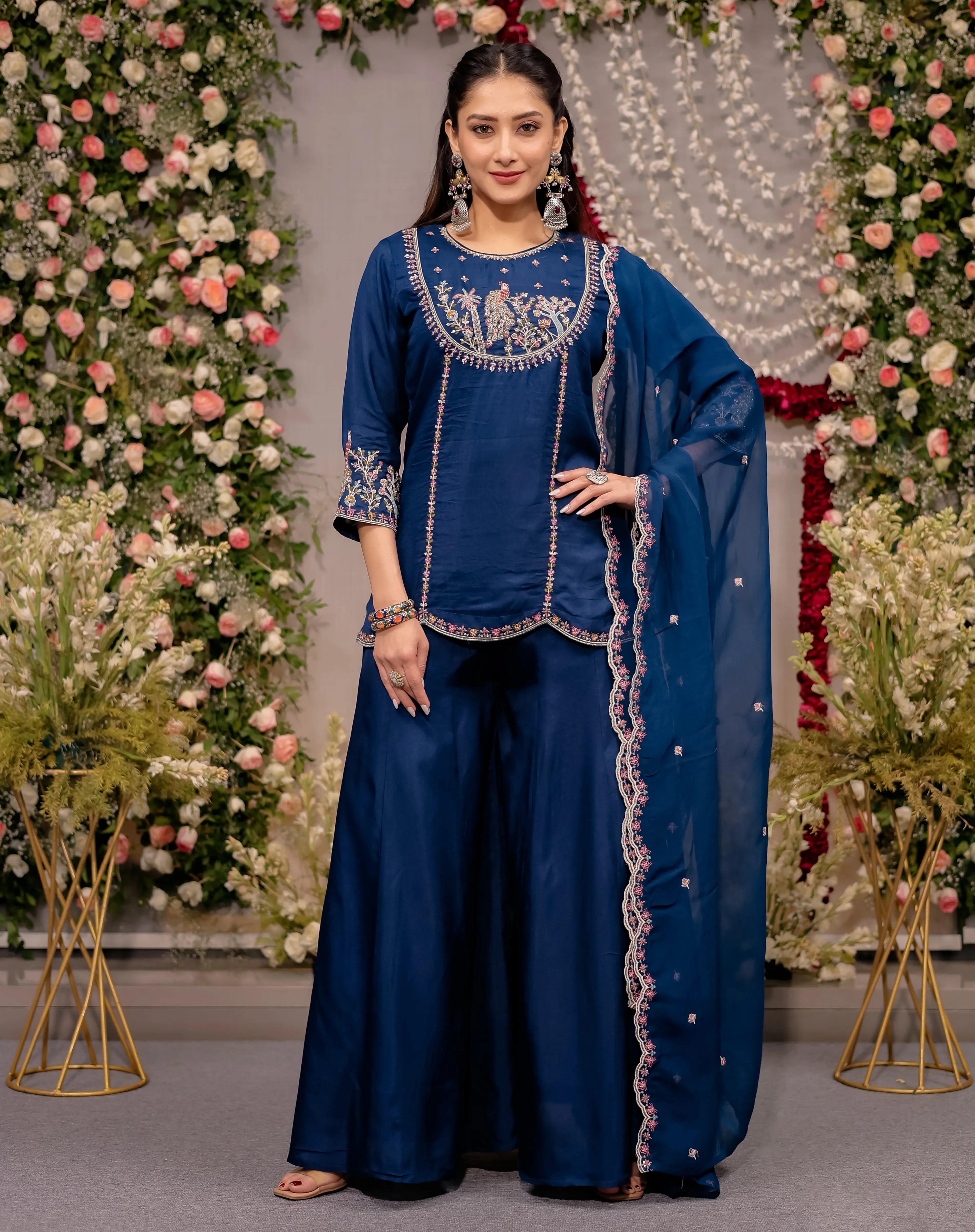Woman in a blue traditional outfit with floral decorations in the background