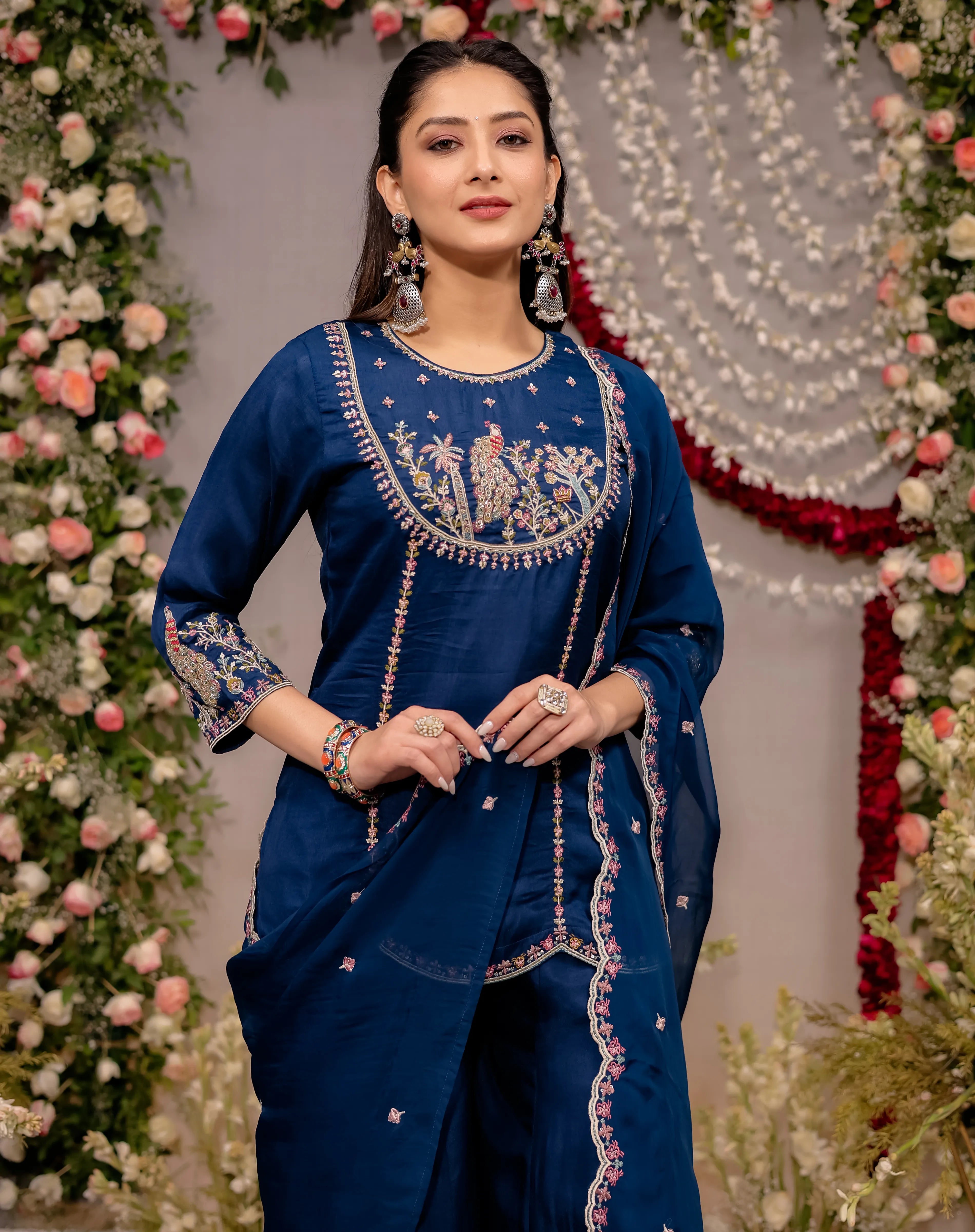 Woman in a blue traditional outfit with floral decorations in the background