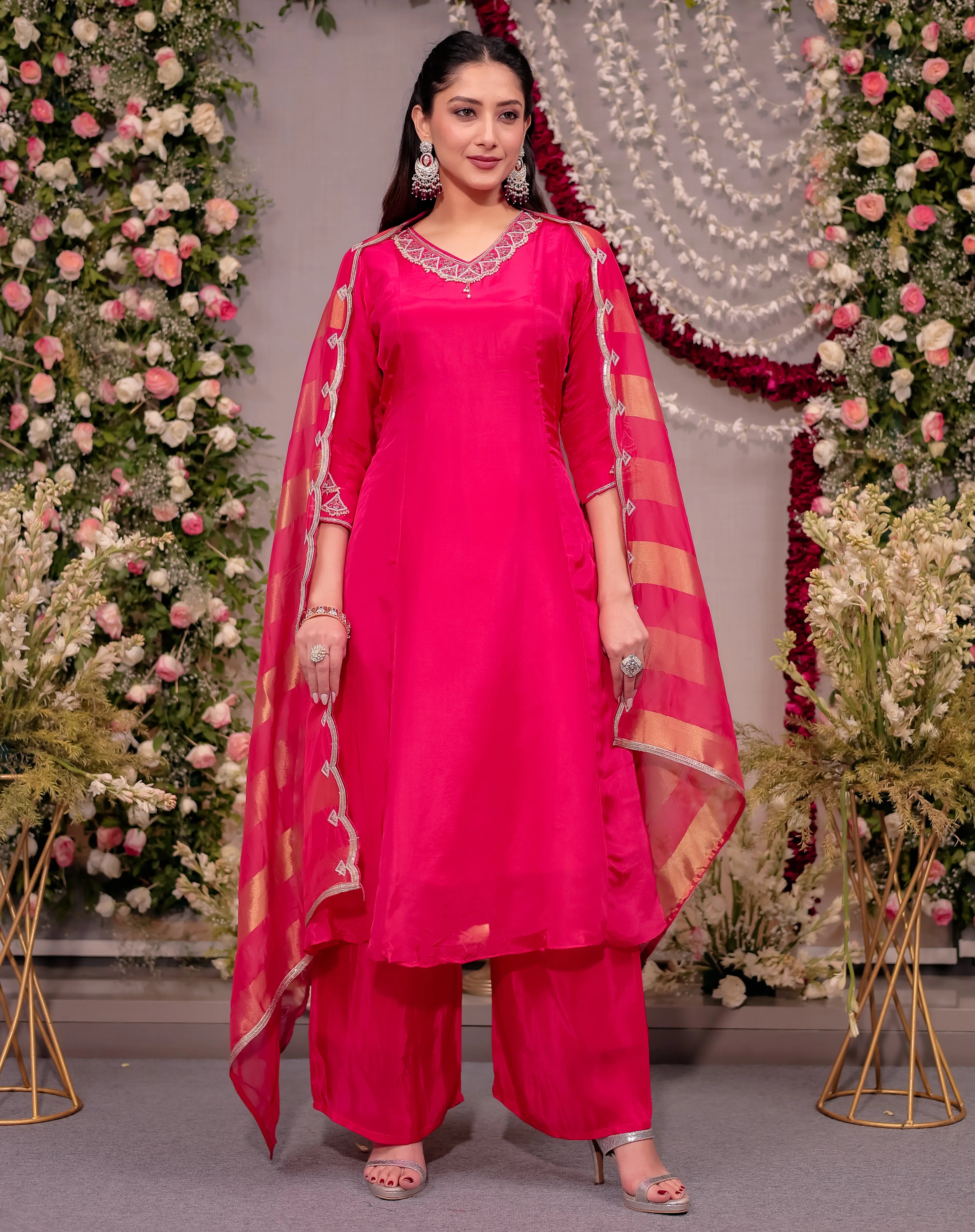 Woman in a bright pink traditional outfit with a floral decorated background