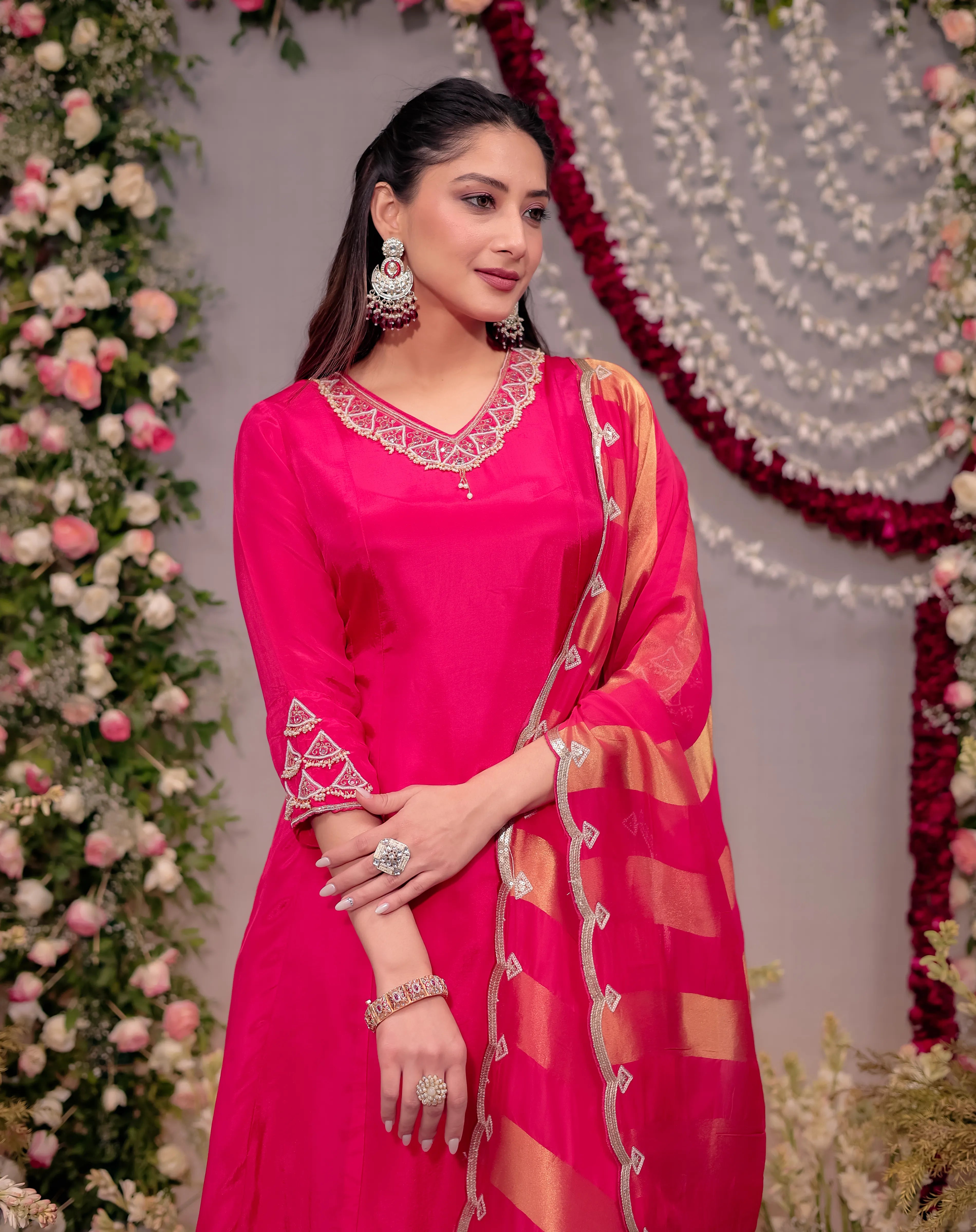 Woman in a bright pink traditional outfit with a floral background