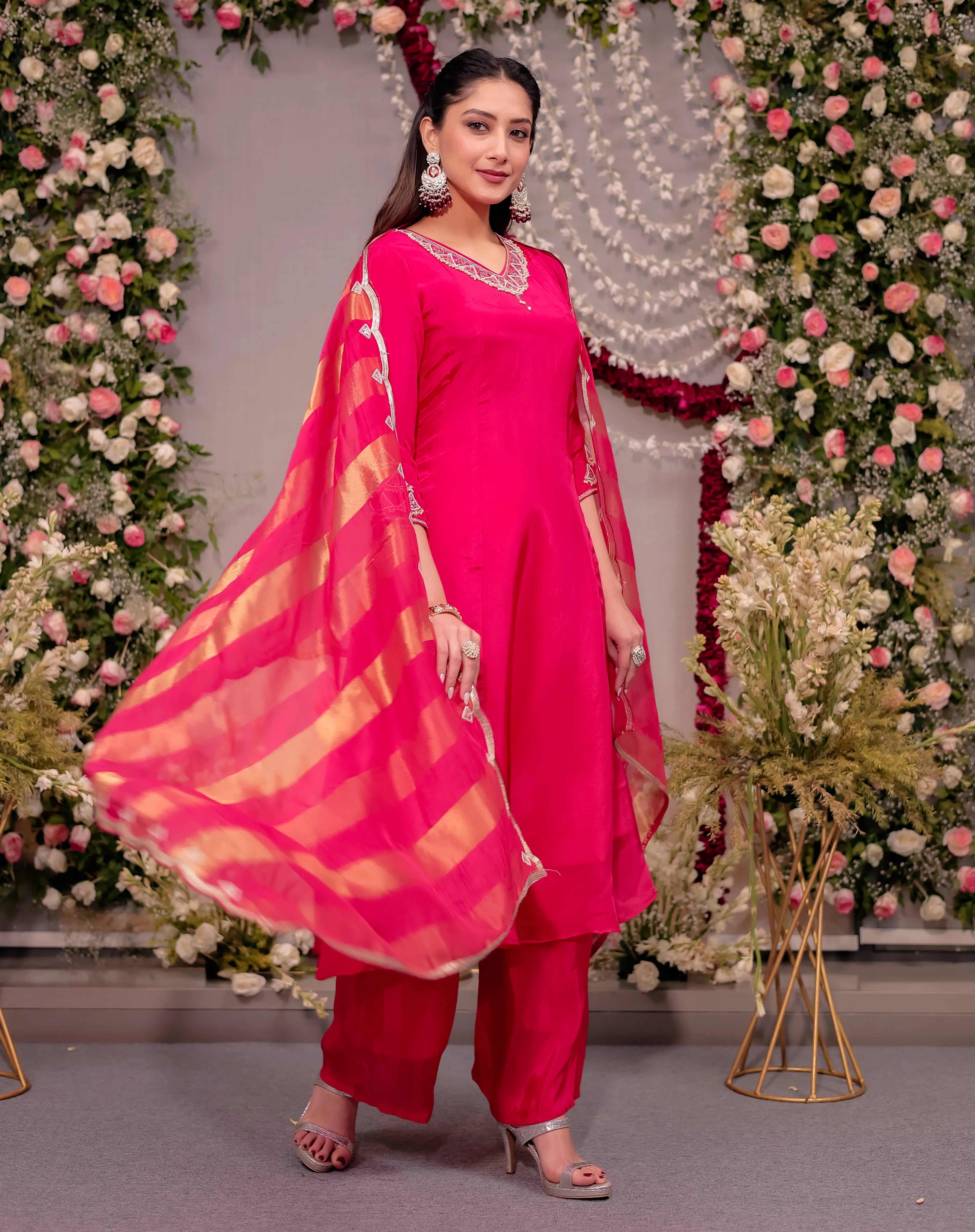 Woman in a bright pink traditional outfit with a floral decorated background