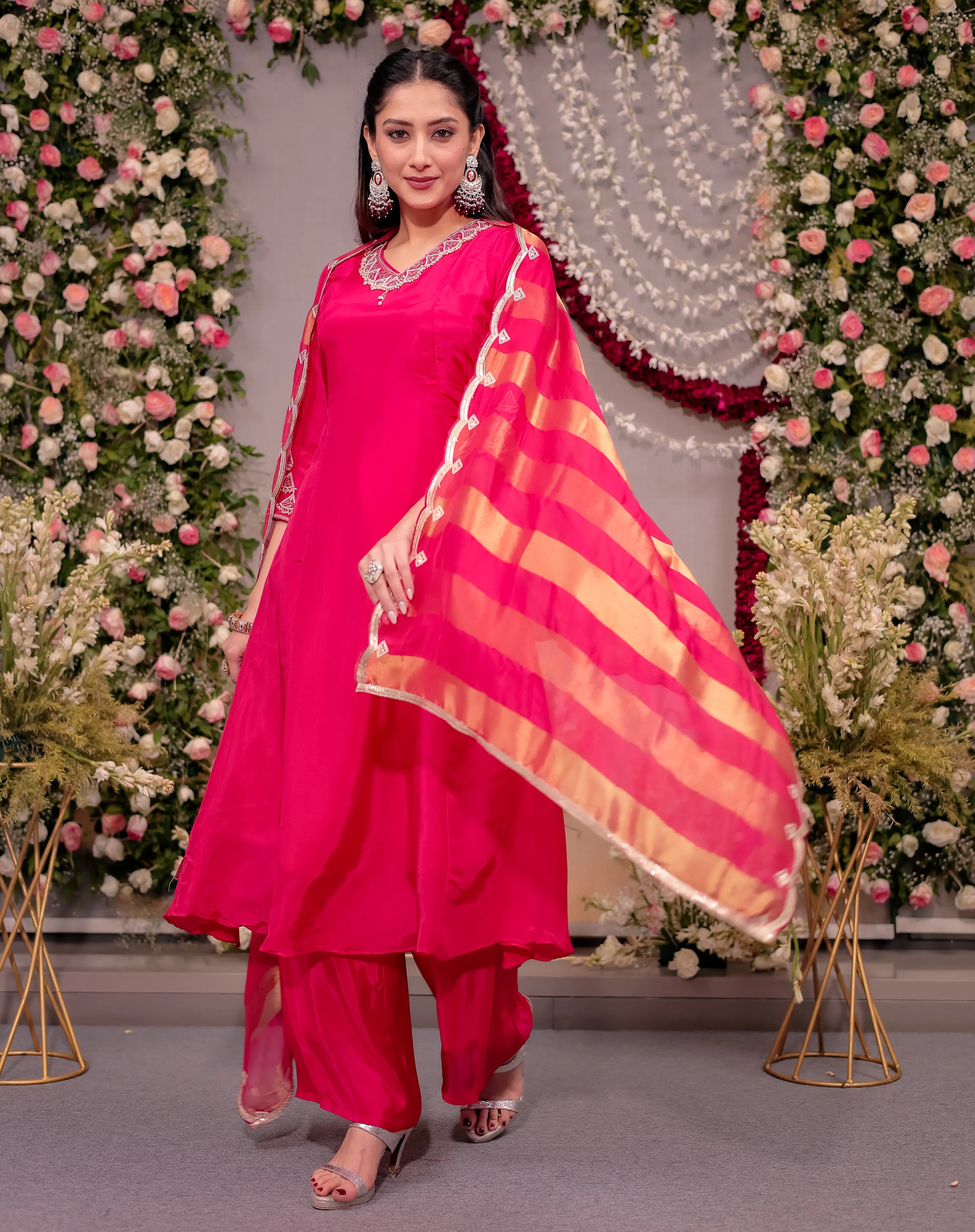 Woman in a bright pink traditional outfit with a floral decorated background