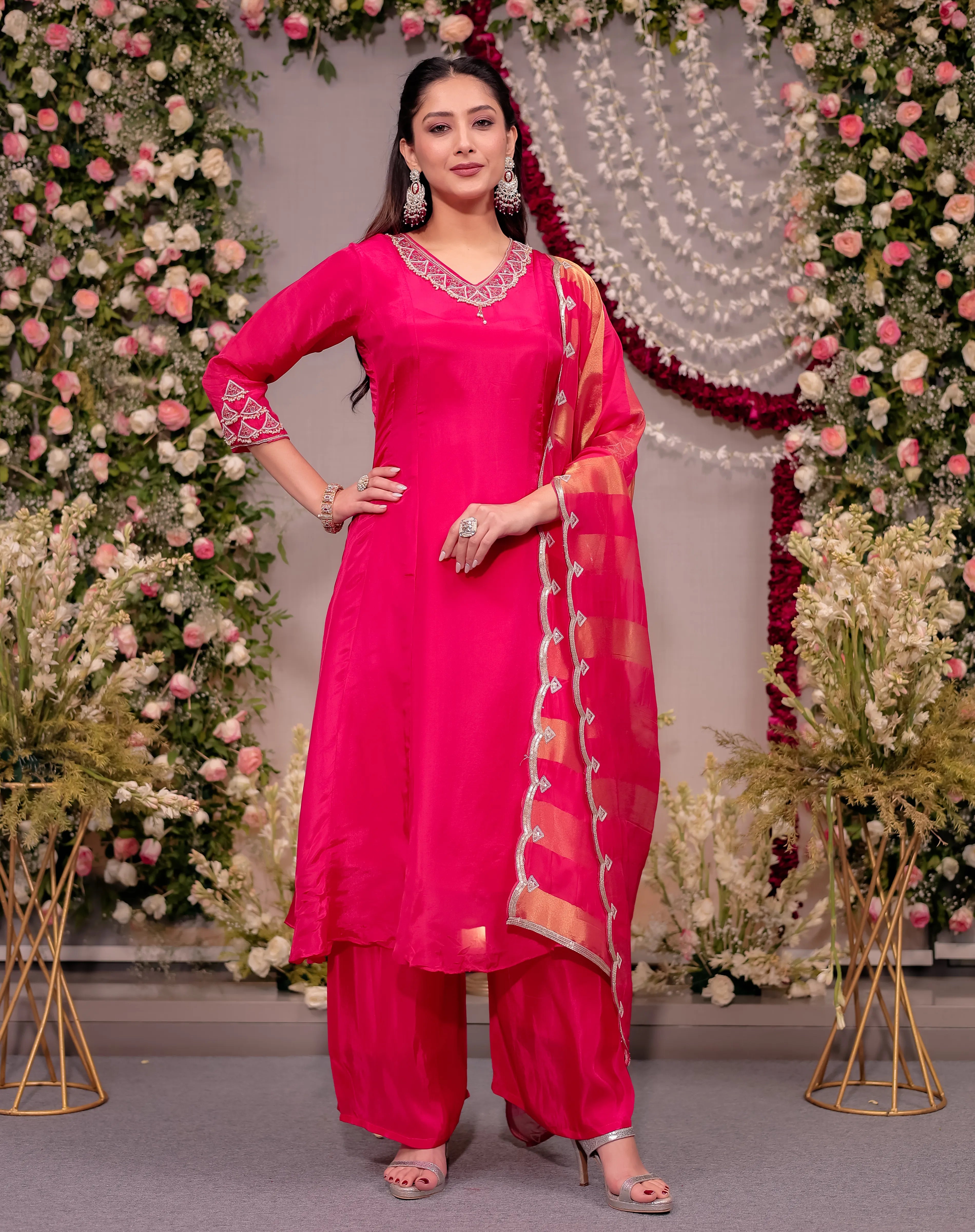 Woman in a bright pink traditional outfit with floral decorations in the background