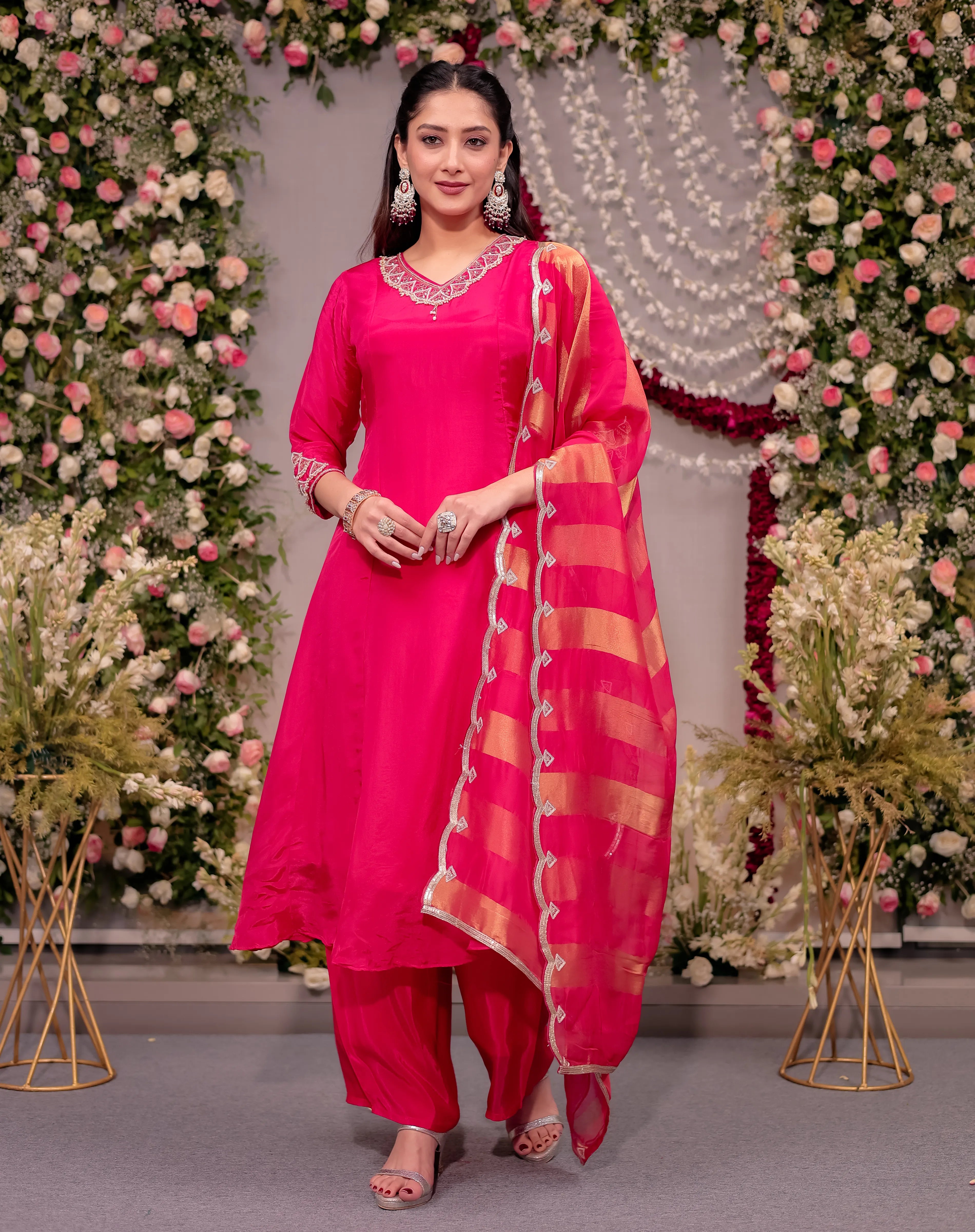 Woman in a bright pink traditional outfit with a floral decorated background