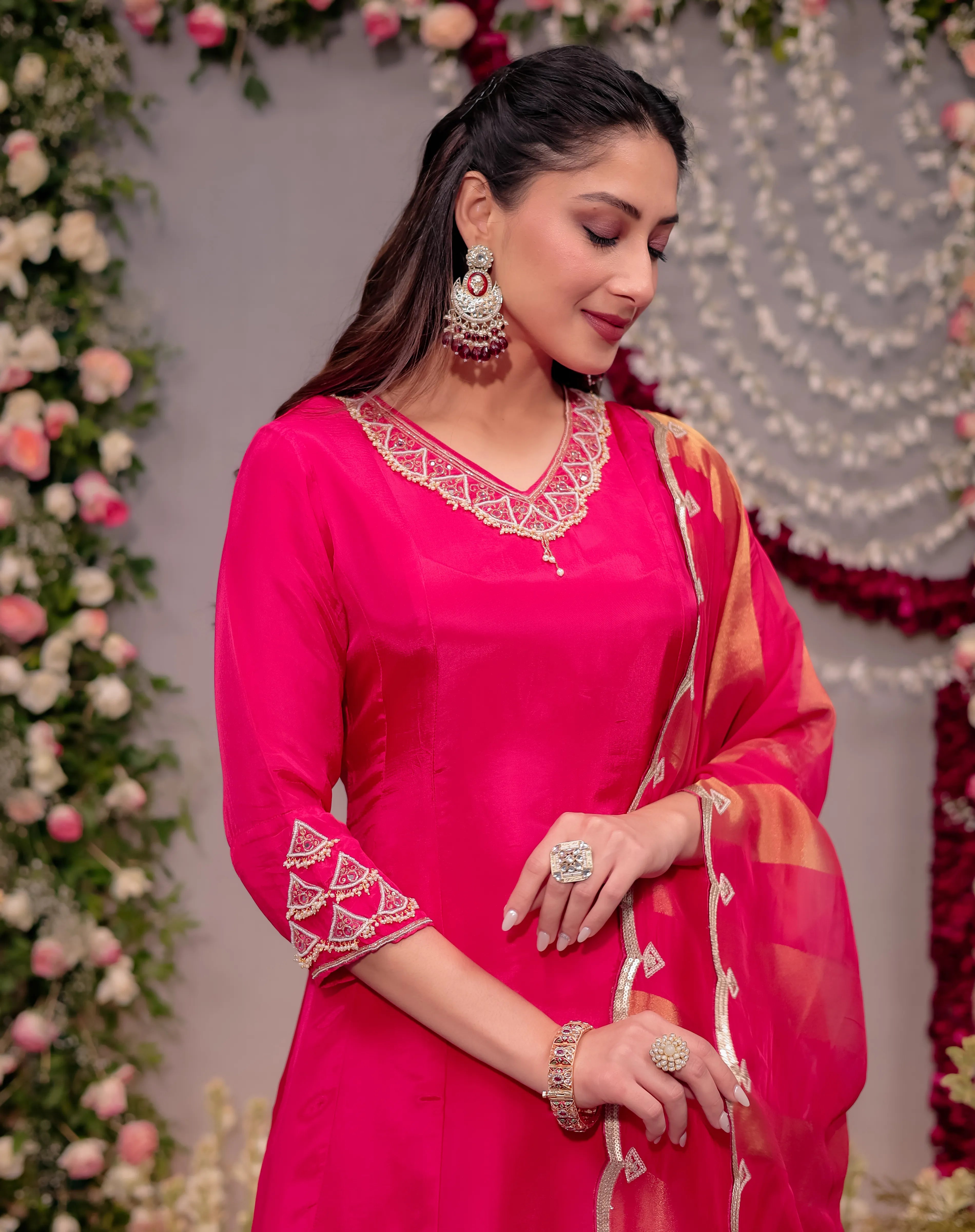 Woman in a pink traditional outfit with floral decorations in the background