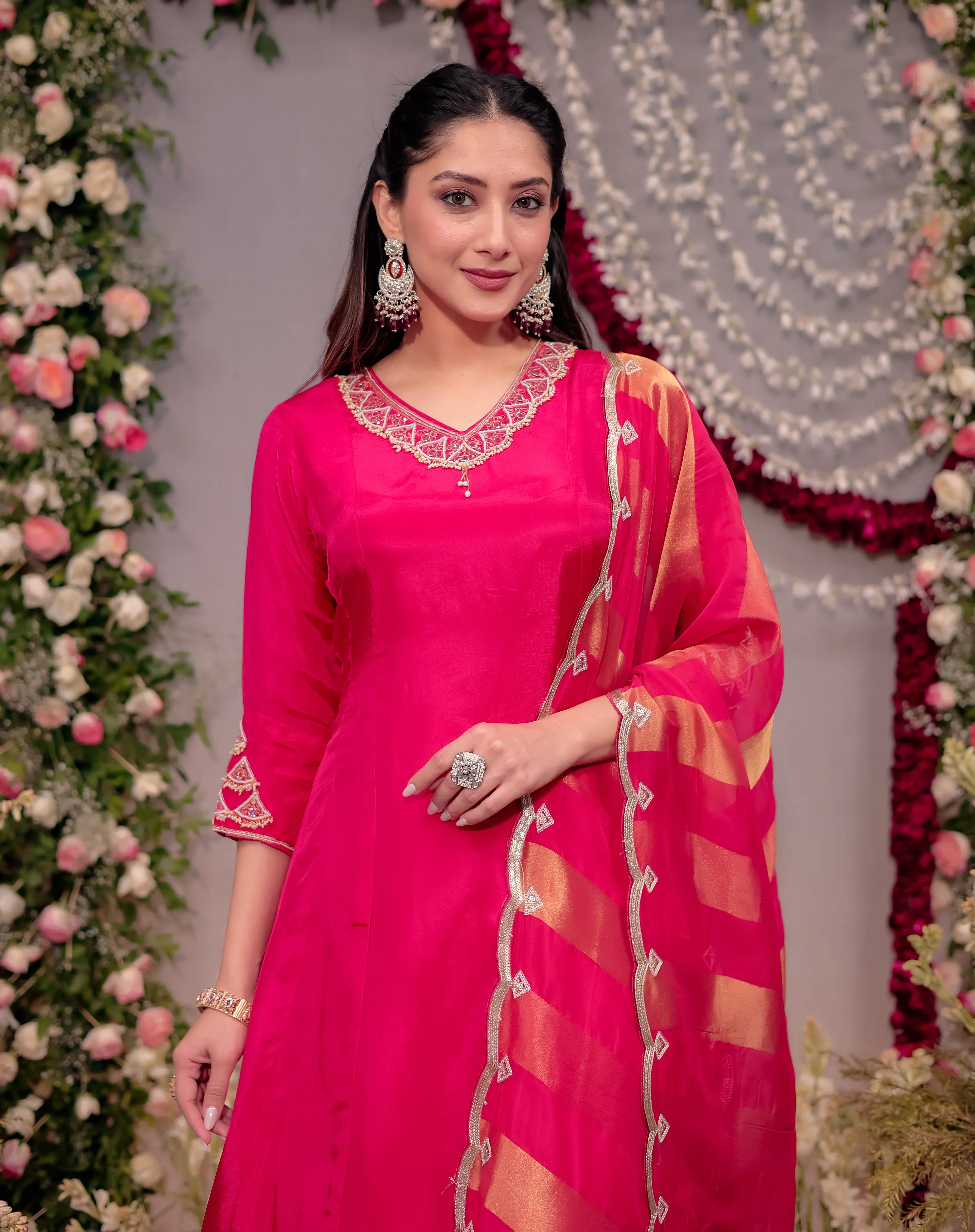 Woman in a pink traditional outfit with floral decorations in the background