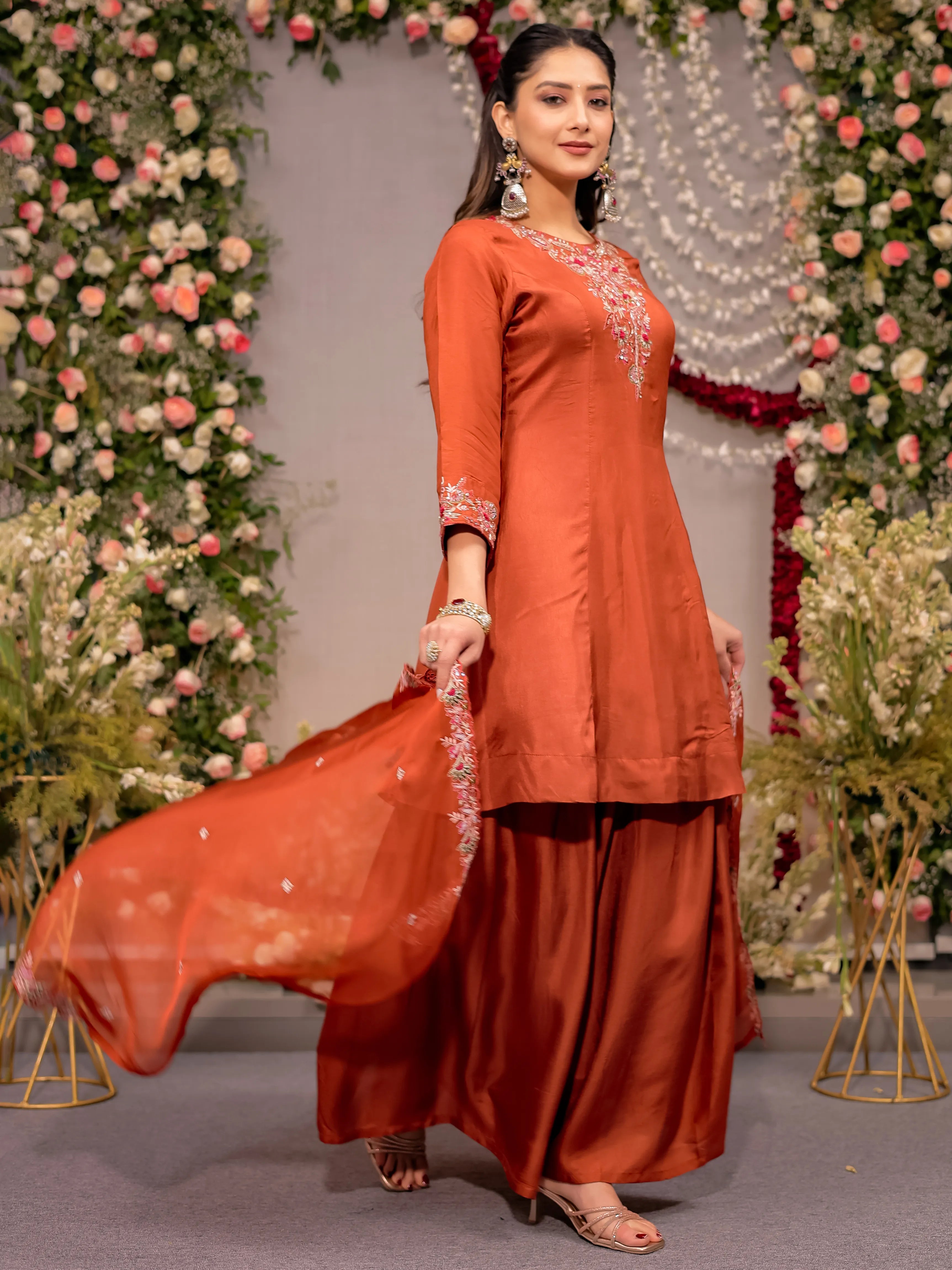 Woman in an orange traditional outfit with a floral decorated background