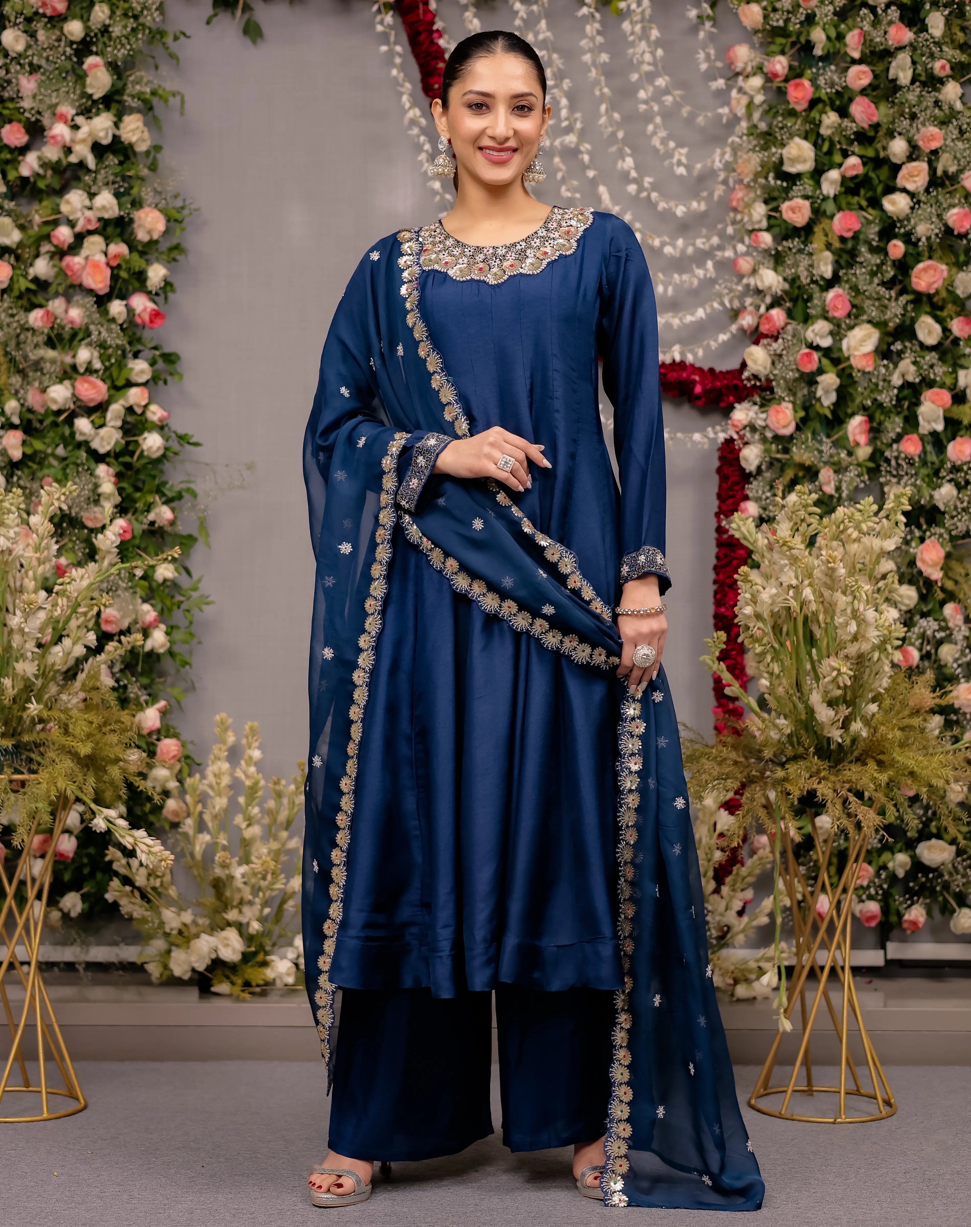 Woman in a blue traditional outfit with floral decorations in the background