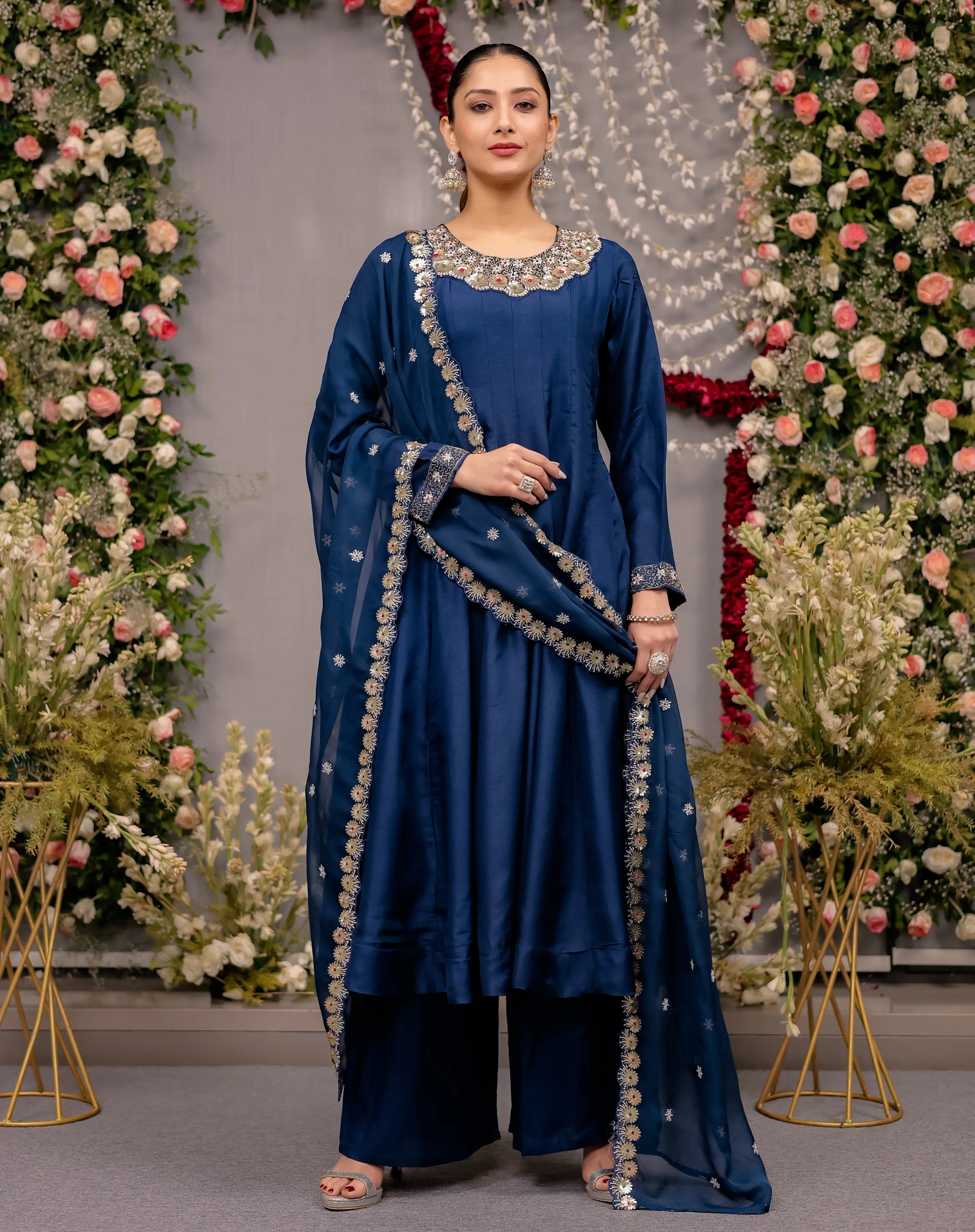 Woman in a blue traditional outfit with floral decorations in the background