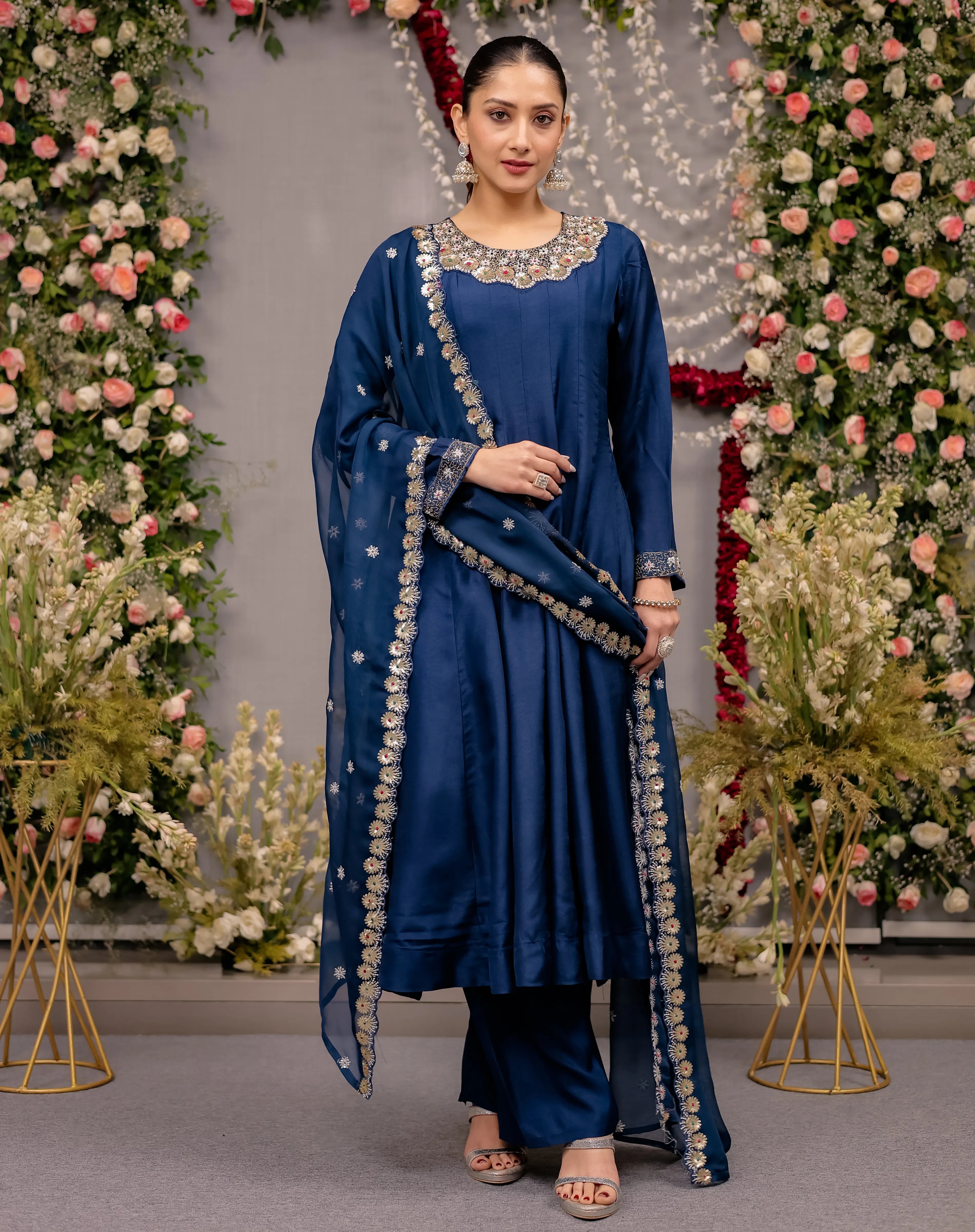 Woman in a blue traditional outfit with floral decorations in the background