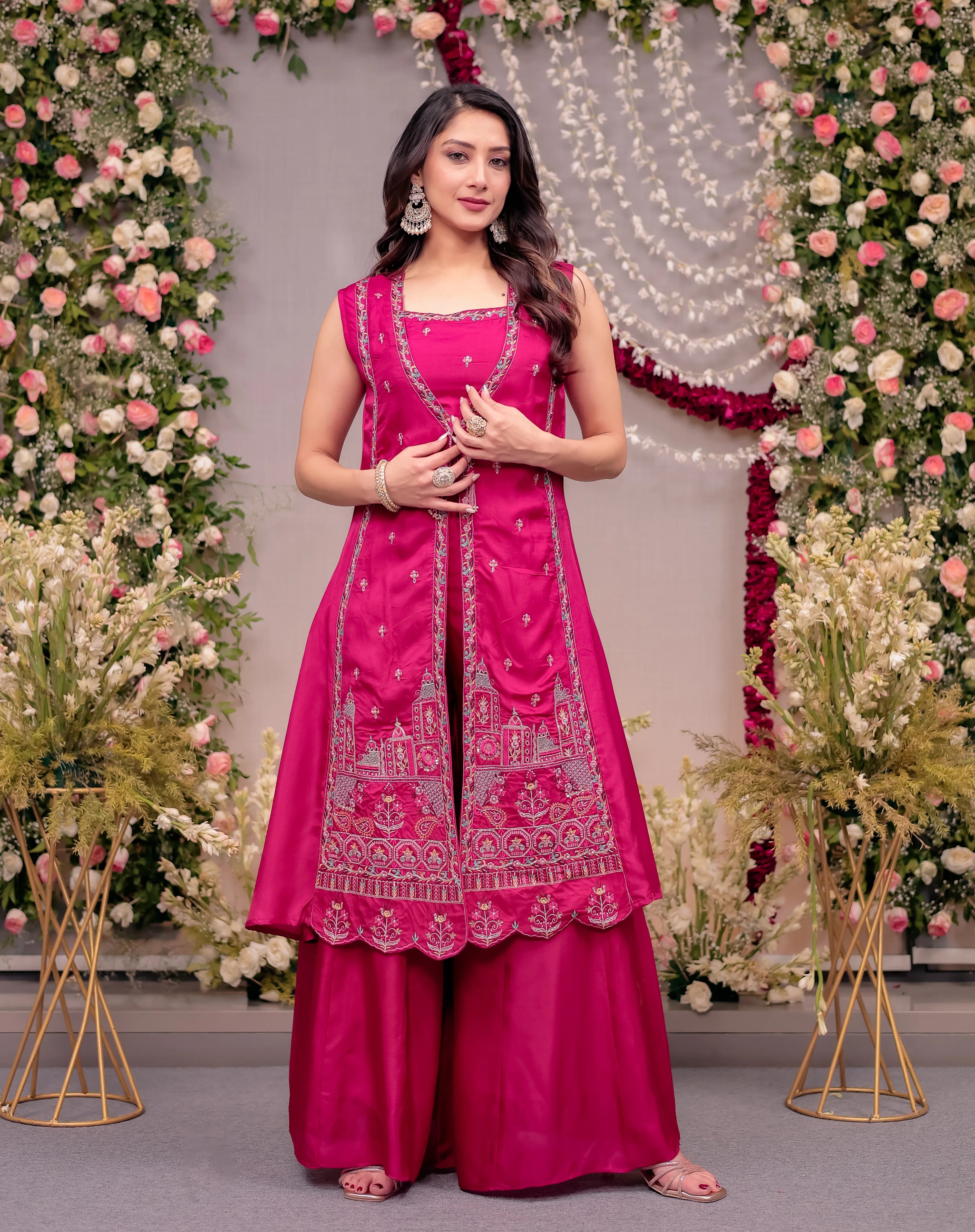 Woman in a pink traditional outfit standing in front of floral decorations