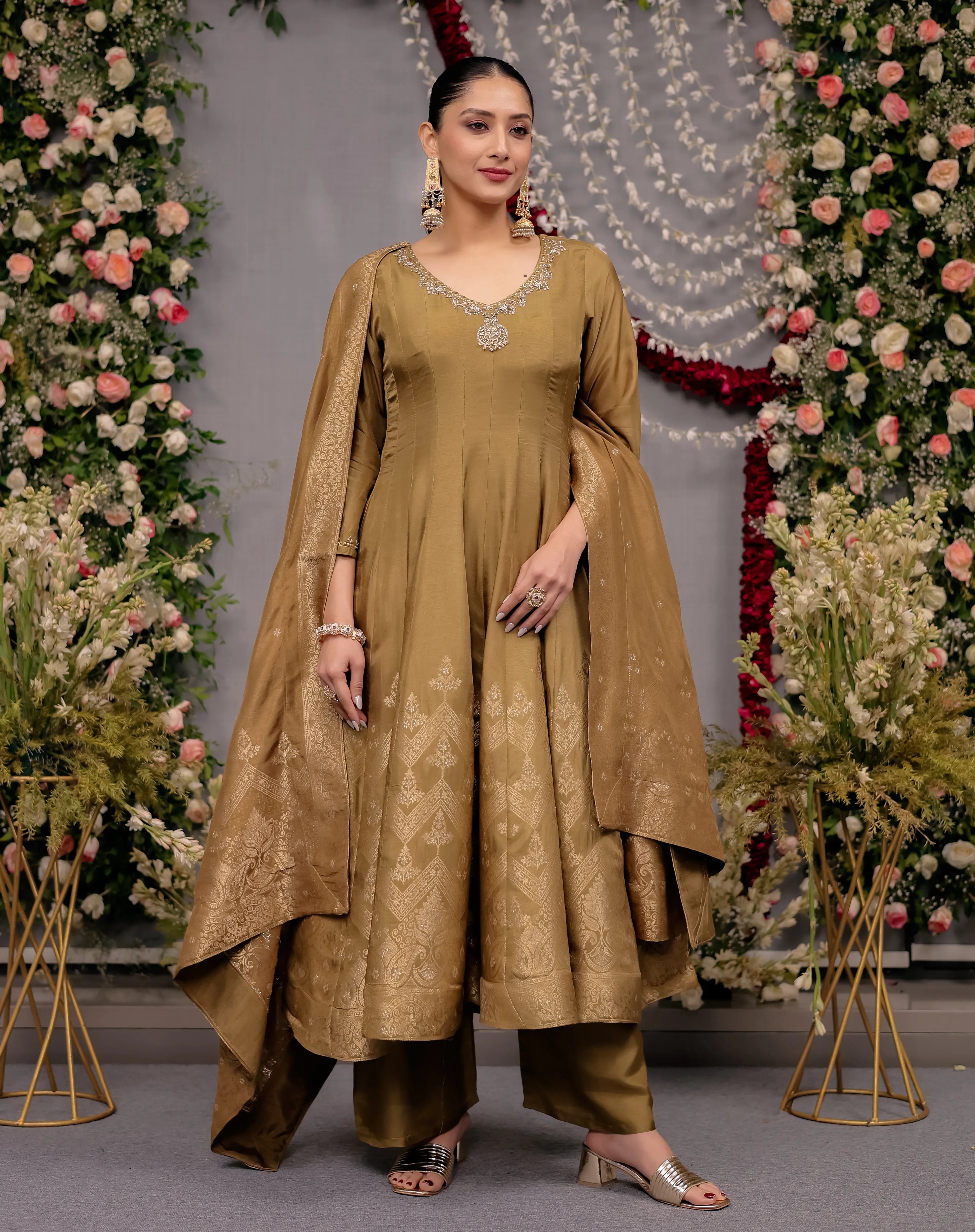 Woman in a traditional outfit standing in front of floral decorations