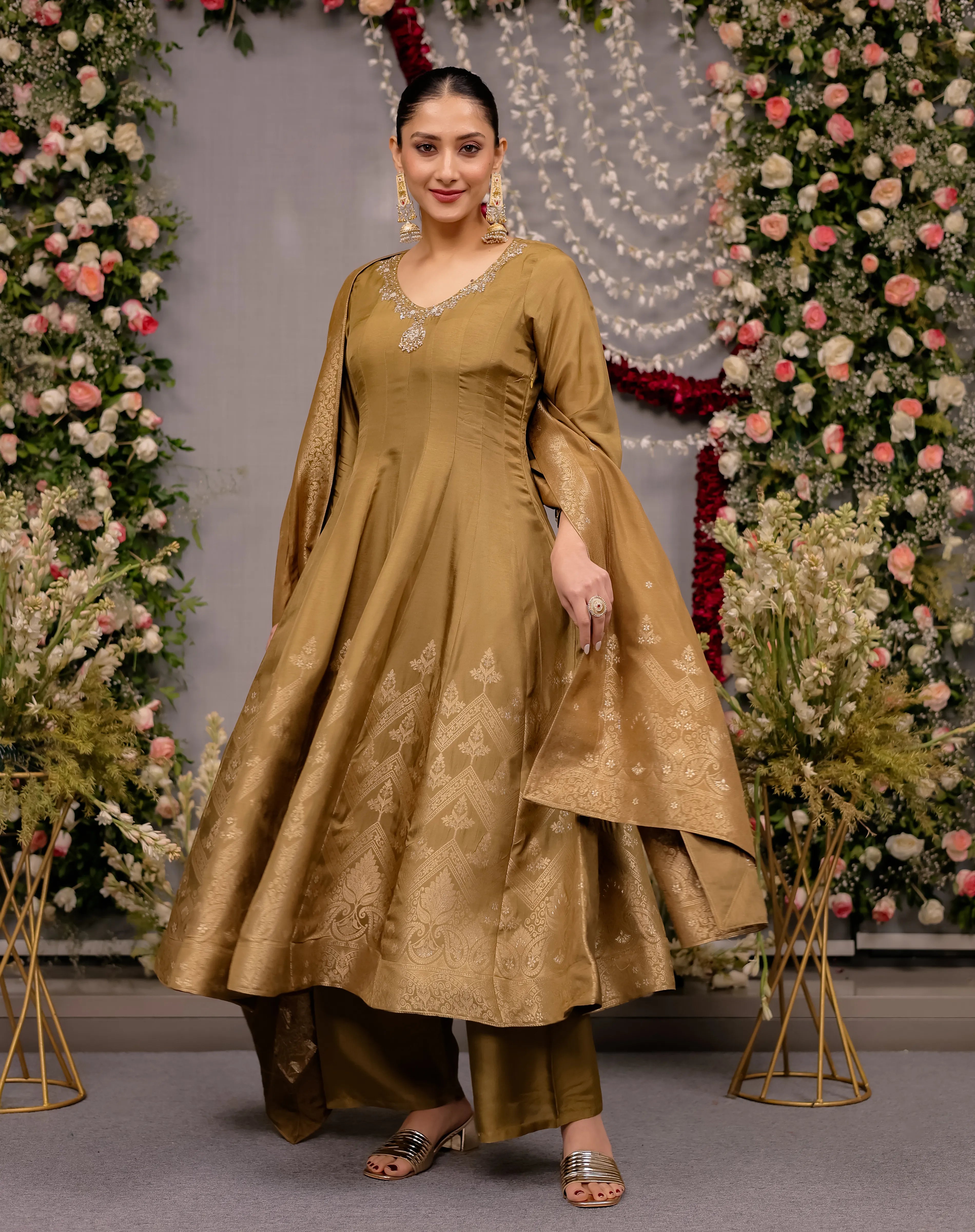 Woman in a traditional outfit standing in front of floral decorations
