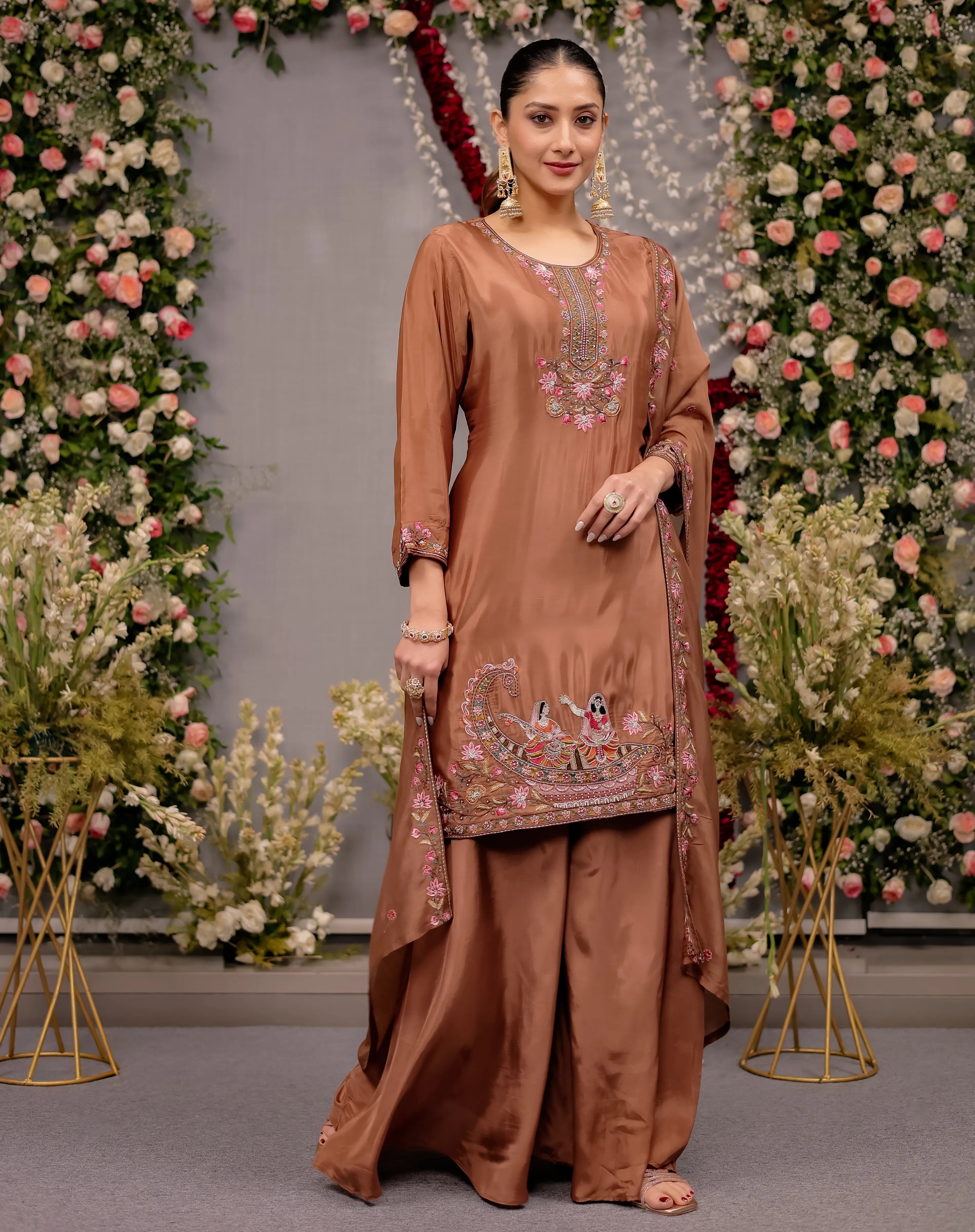 Woman in a brown traditional outfit with floral decorations against a floral backdrop