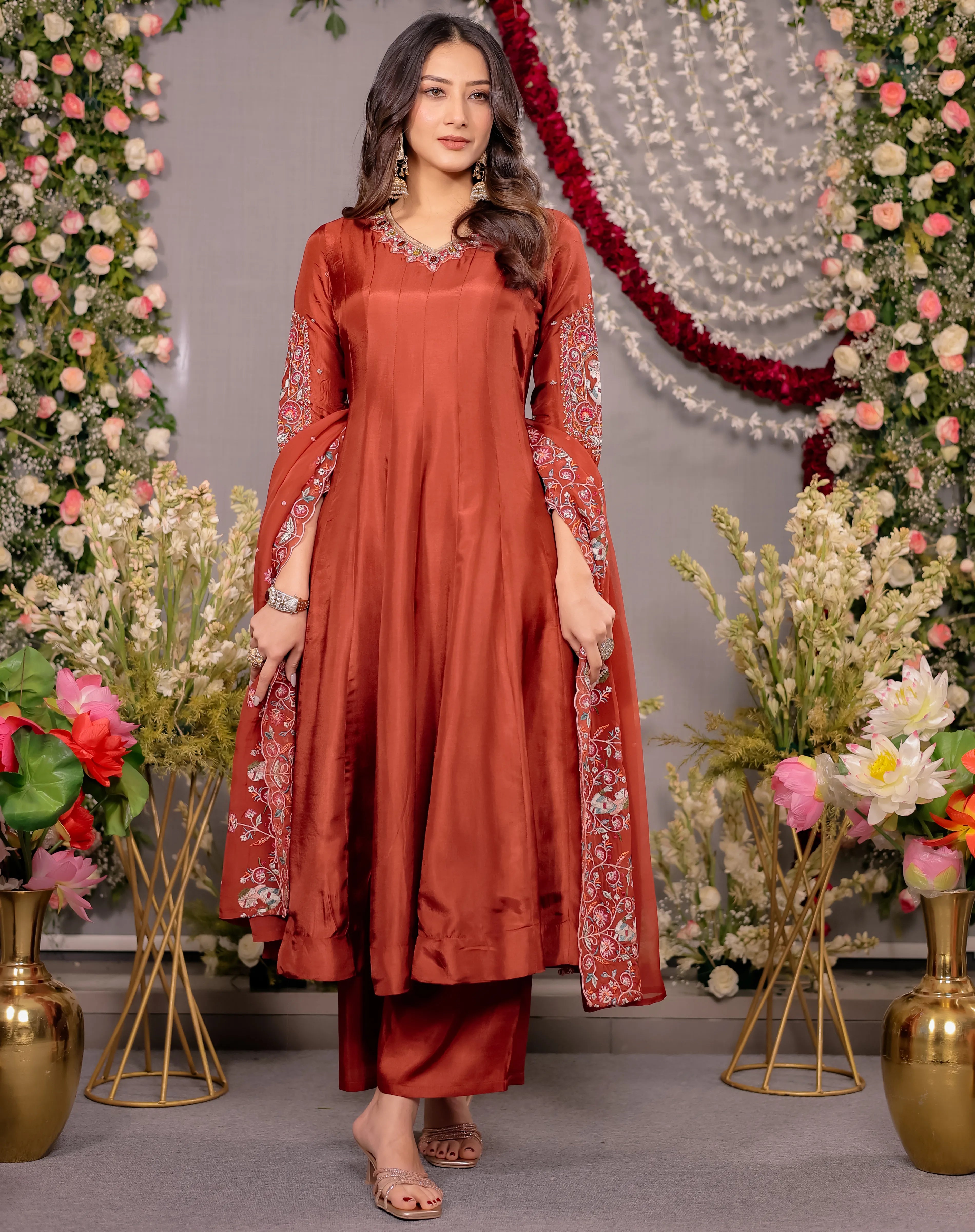 Woman in a red traditional outfit standing in front of floral decorations