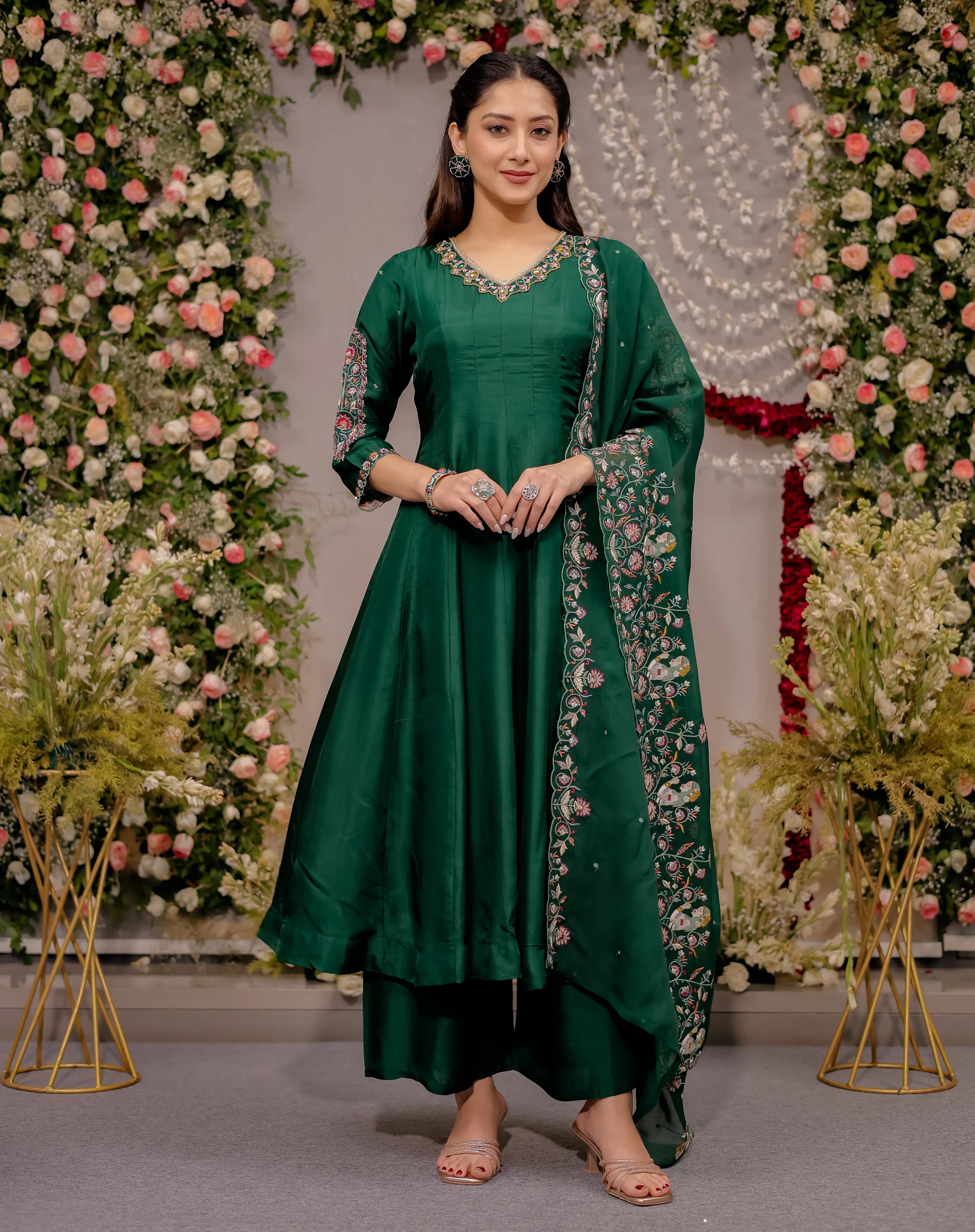 Woman in a green traditional outfit standing in front of floral decorations