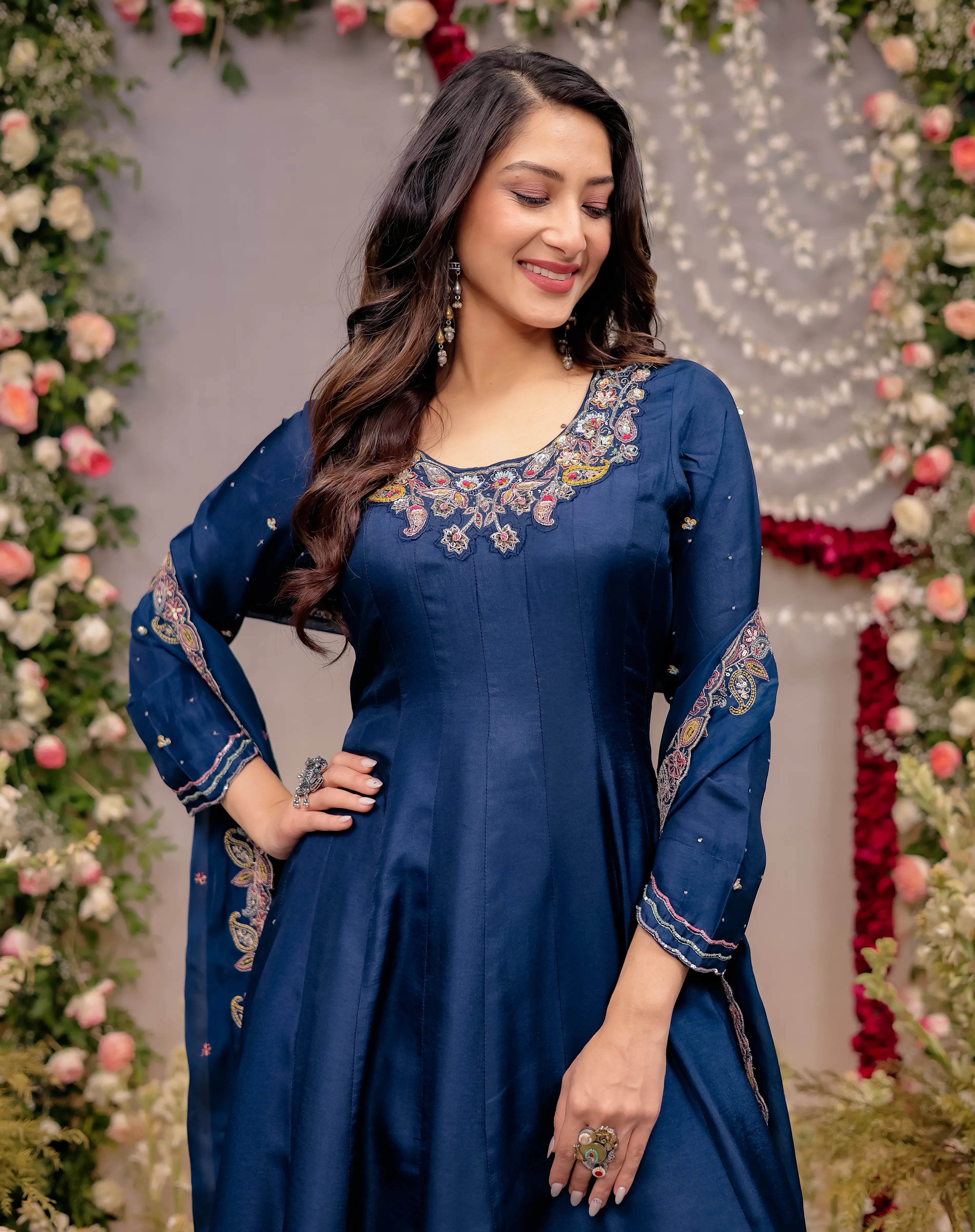 Woman wearing a blue embroidered dress in front of floral decorations