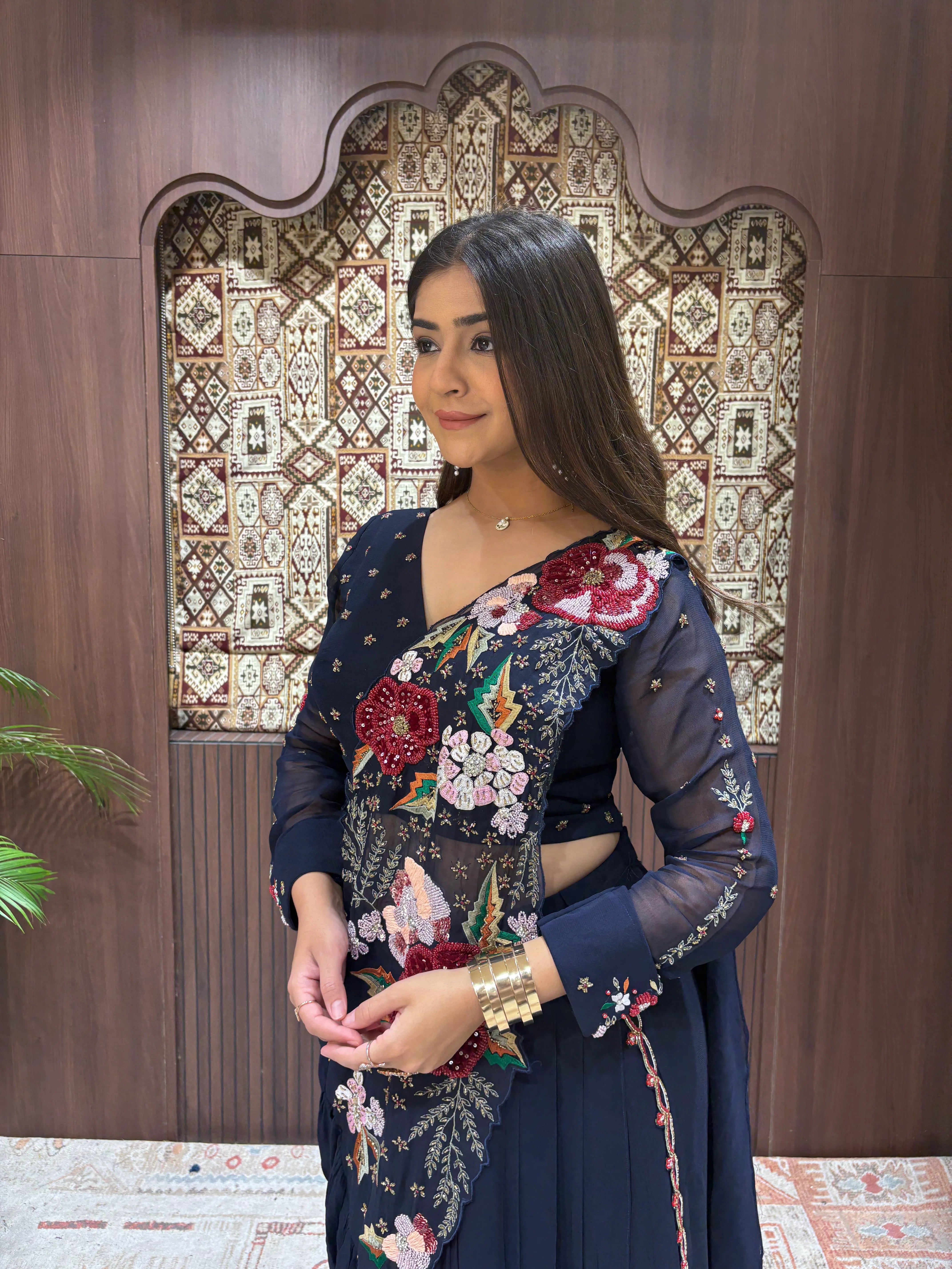 Woman in a floral dress standing in front of an ornate wooden door.