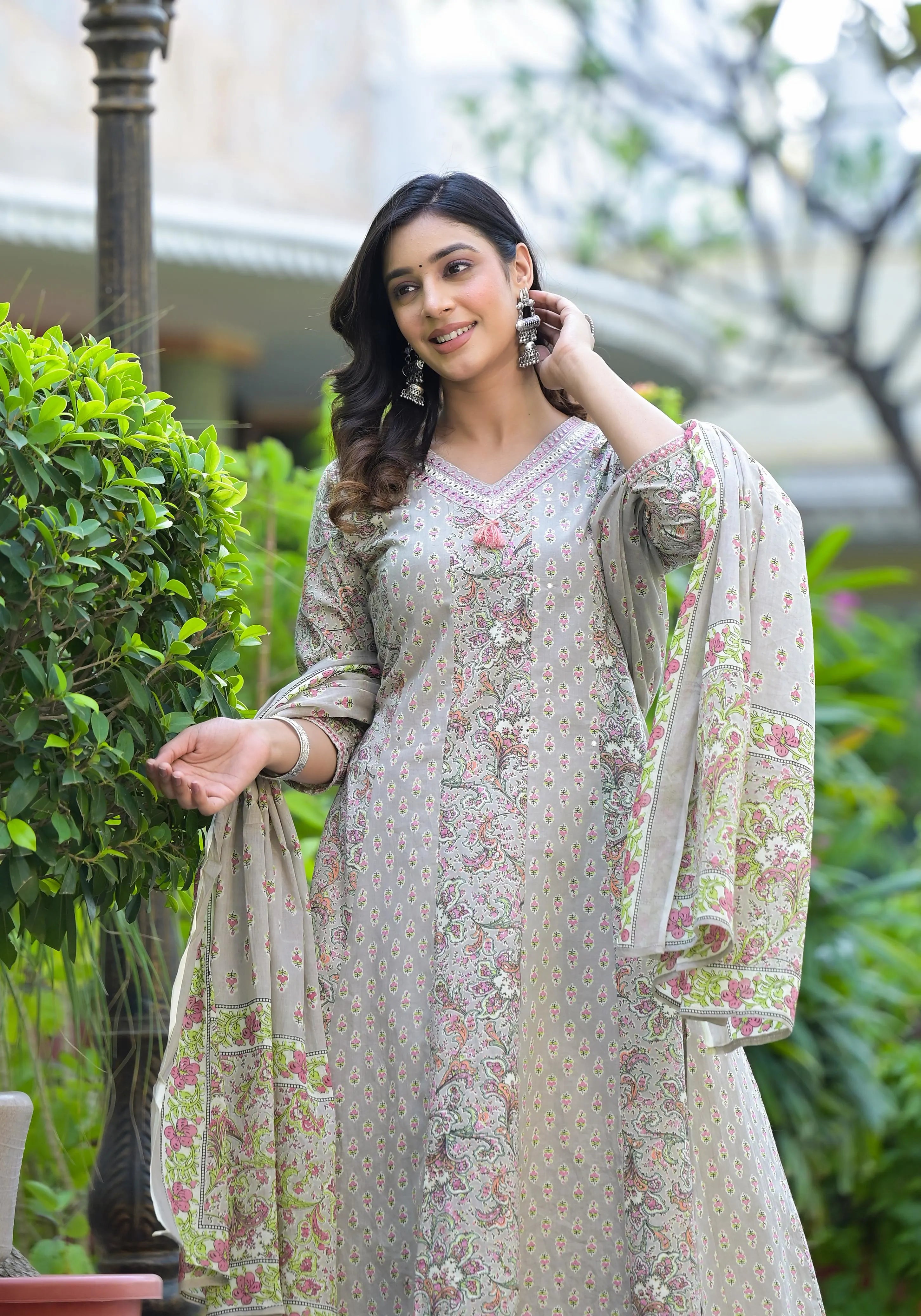 Woman in a floral dress standing outdoors with greenery in the background