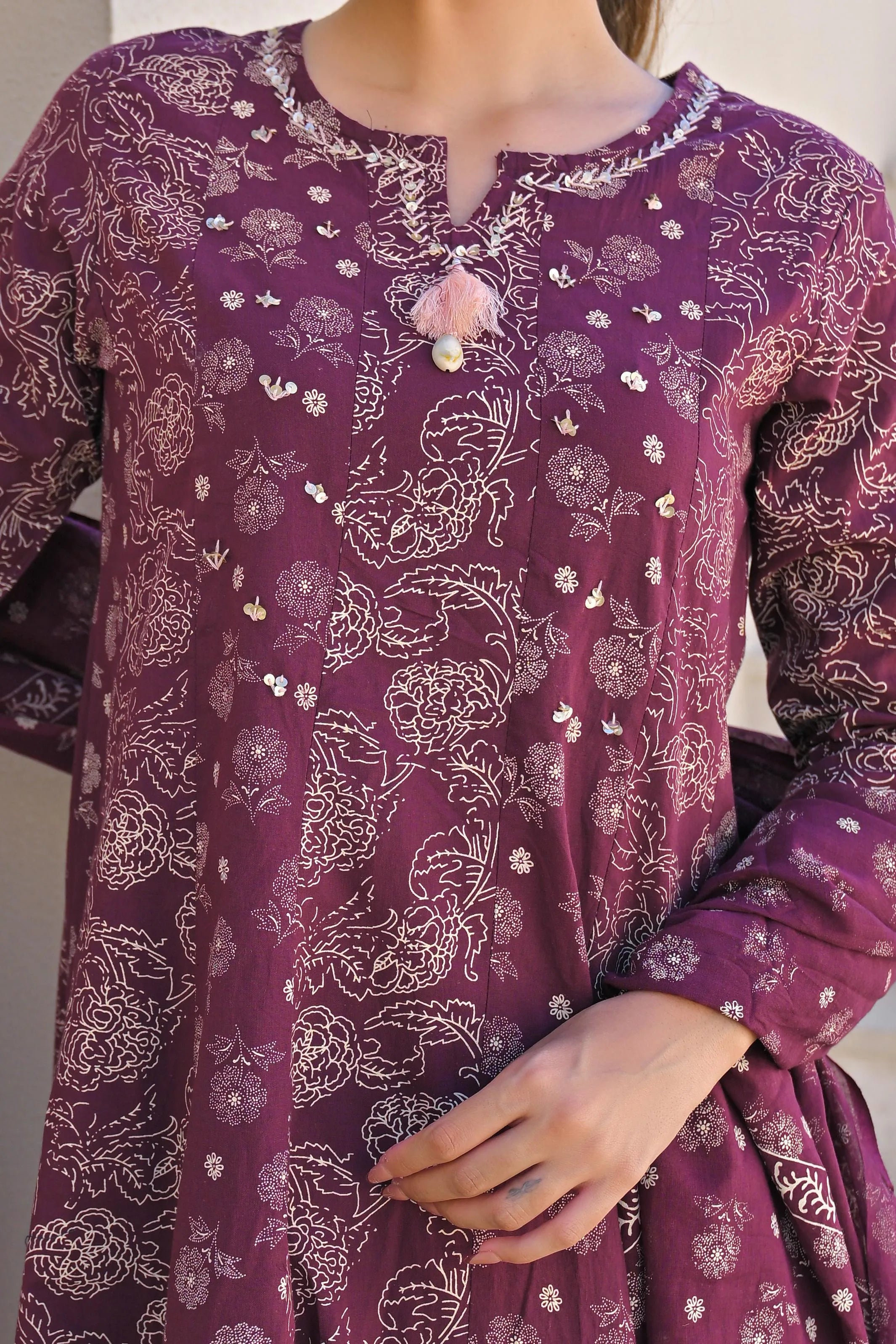 Purple patterned dress with floral designs on a plain background