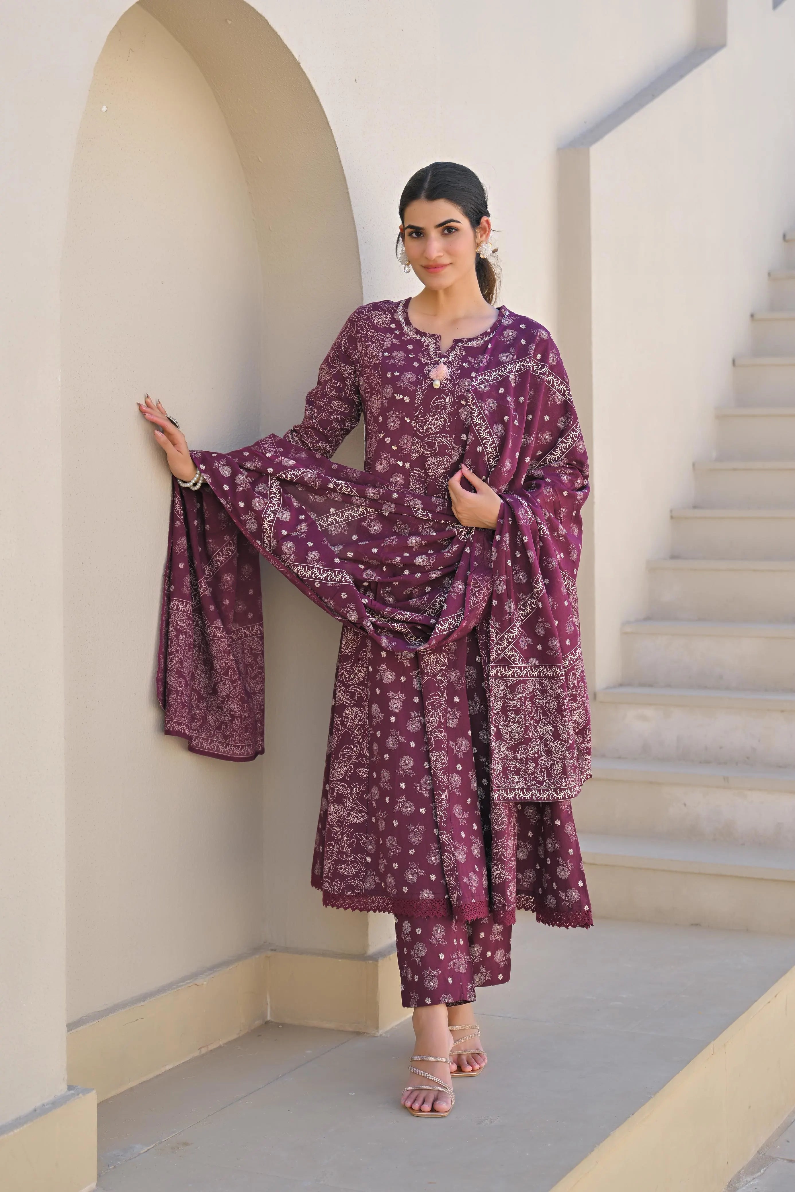 Woman in a purple traditional outfit standing in an architectural setting.