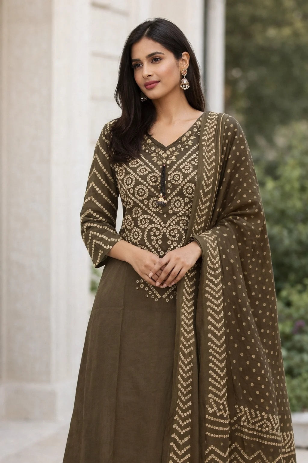 Woman wearing a brown and gold traditional outfit with a patterned shawl outdoors.
