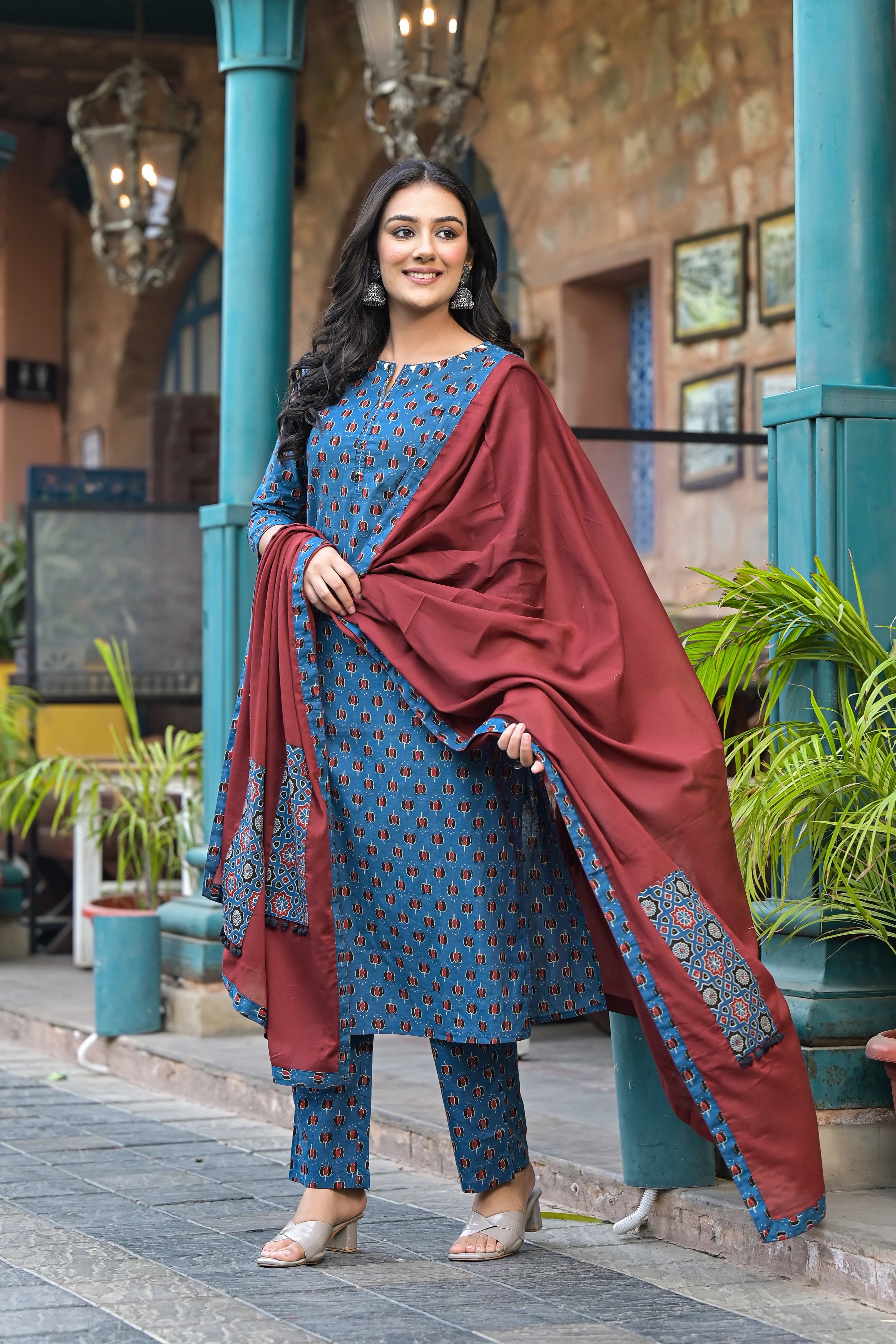 Woman in a blue and red traditional outfit standing outdoors.