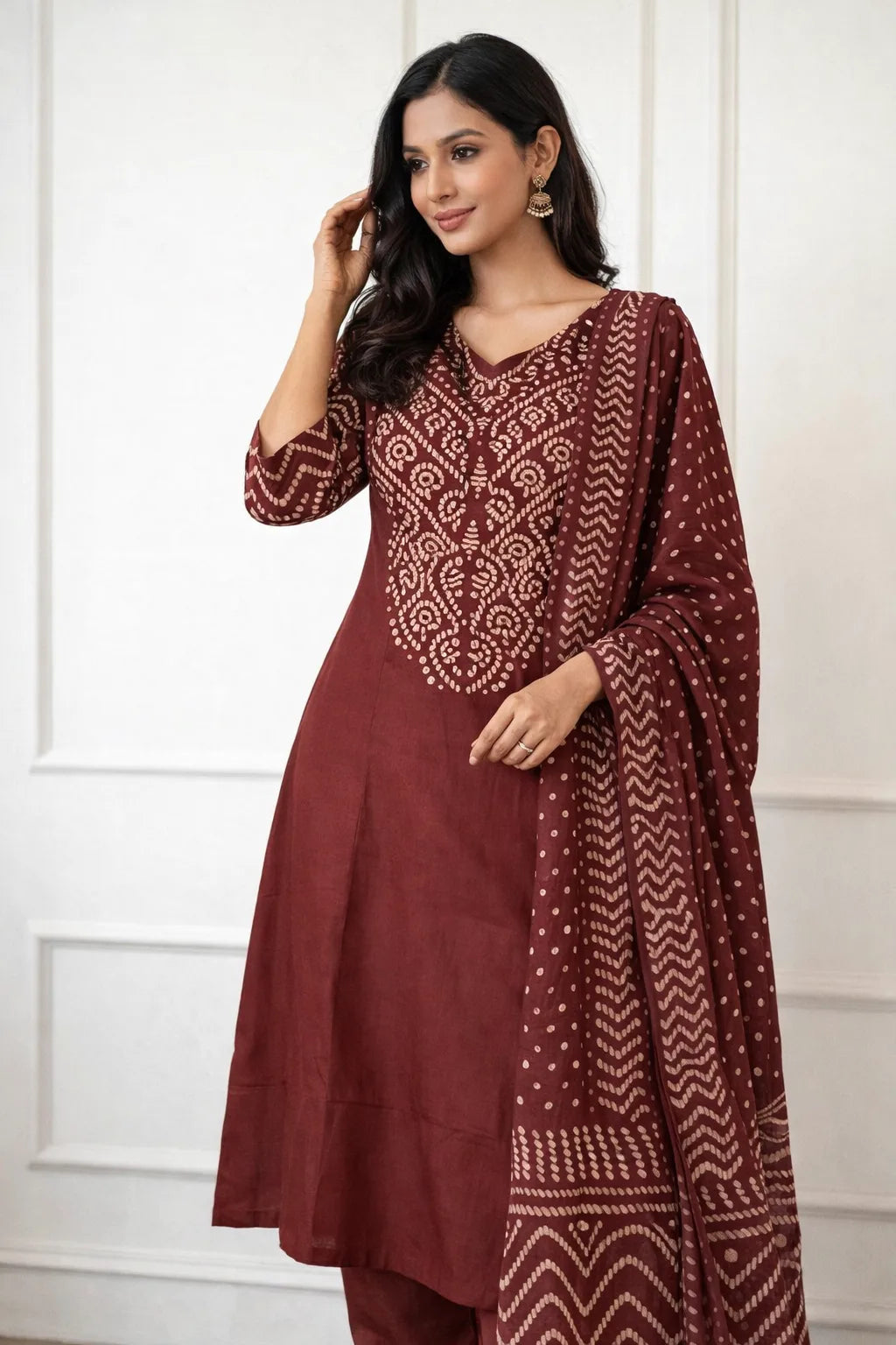Woman wearing a maroon traditional outfit with a matching dupatta against a white background