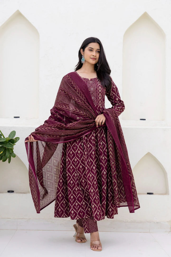 Woman wearing a maroon patterned outfit against a white background