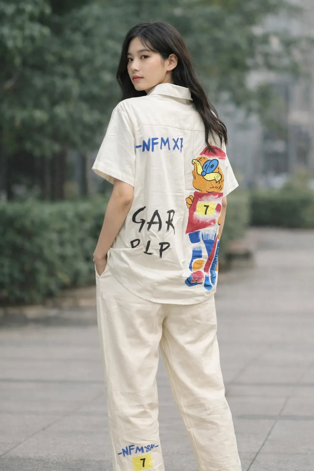 Person wearing a white t-shirt with colorful graphics and text, standing outdoors.