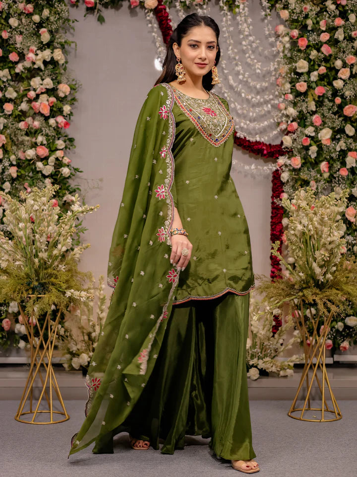 Woman in a green traditional outfit with floral decorations in the background