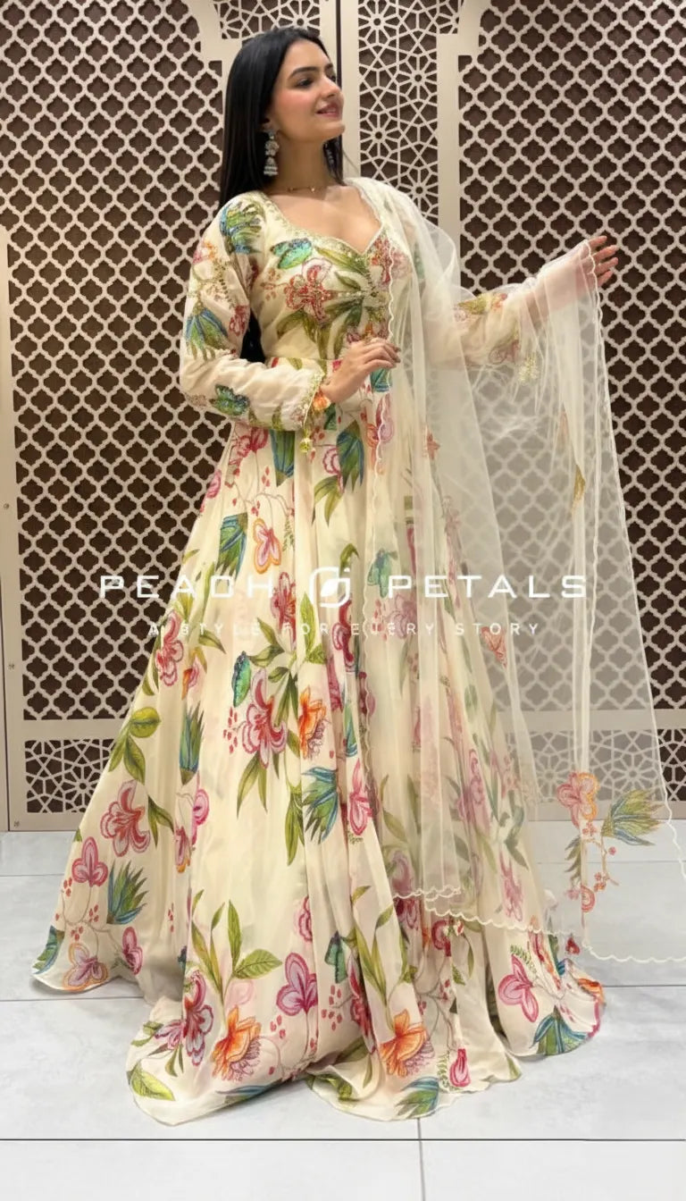 Cream-colored Indo-Western gown featuring vibrant pastel floral prints, long sleeves, and a matching sheer scalloped dupatta.