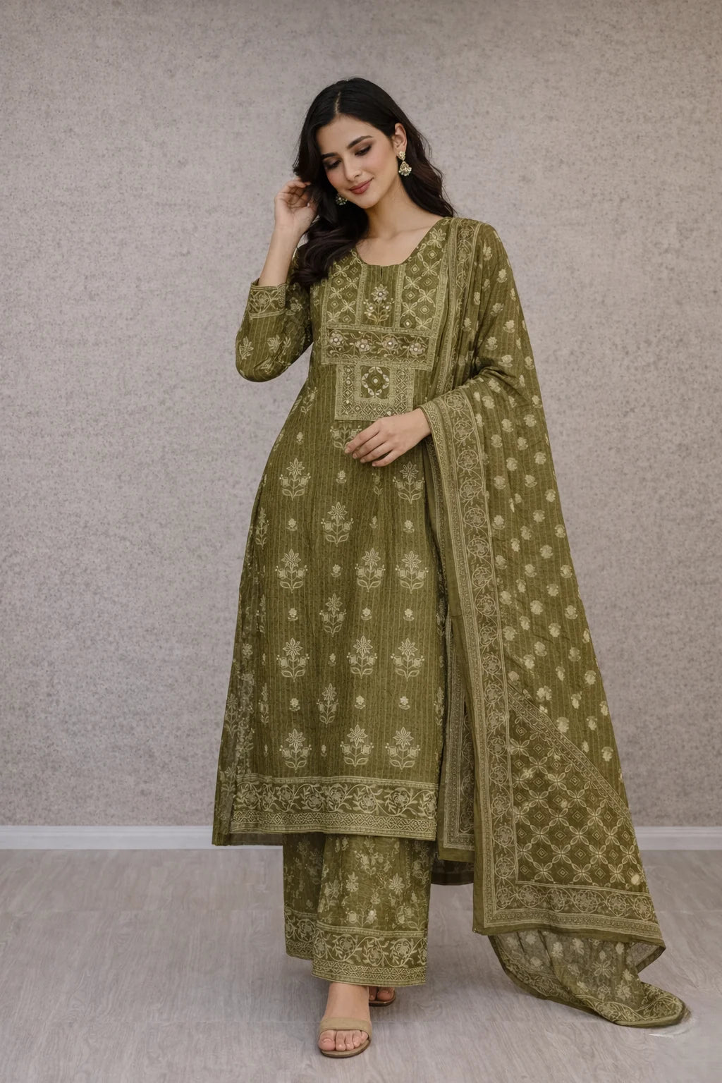 Woman wearing a green embroidered traditional outfit against a plain background